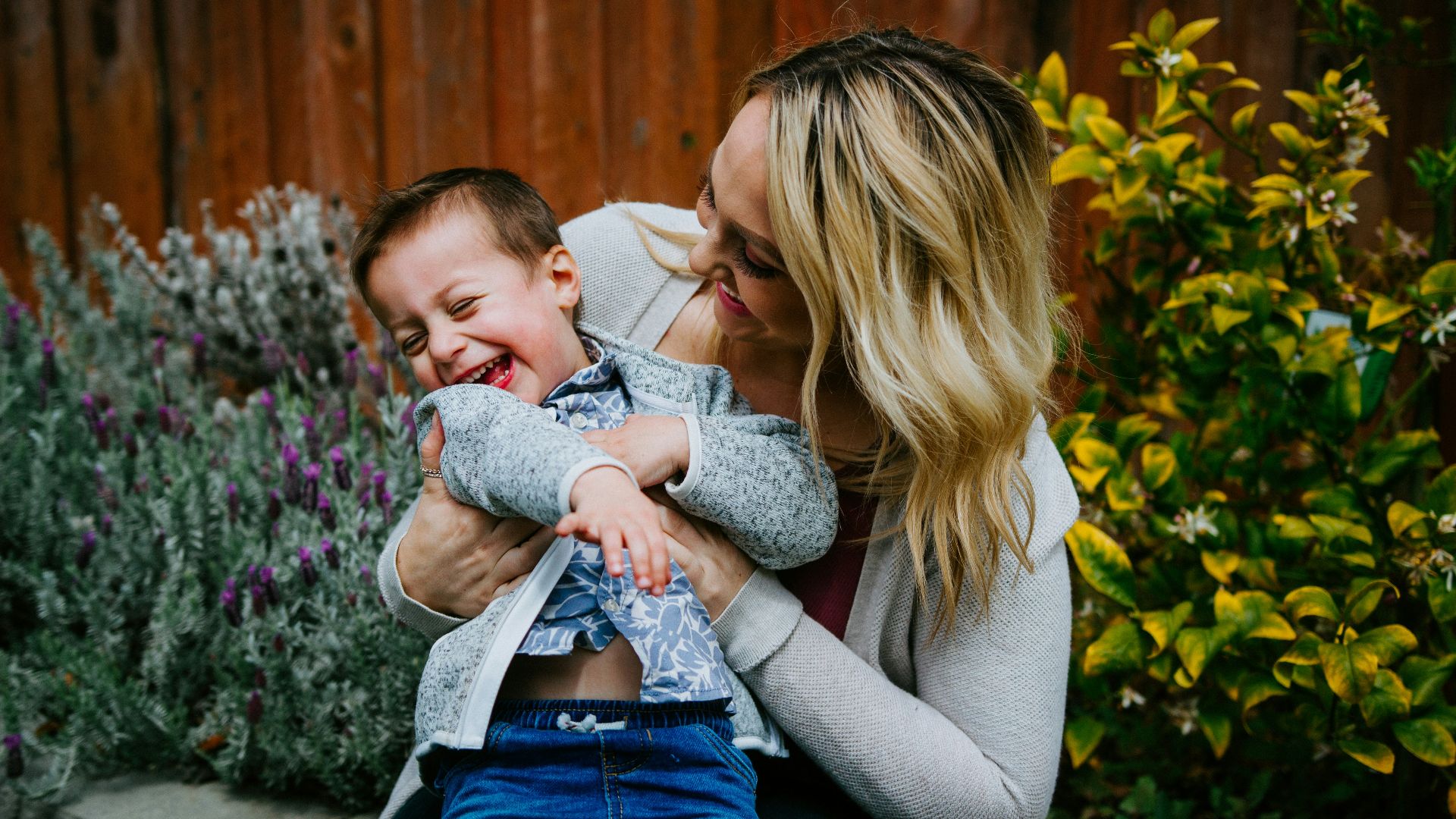 woman in gray sweater carrying baby in blue and white shirt