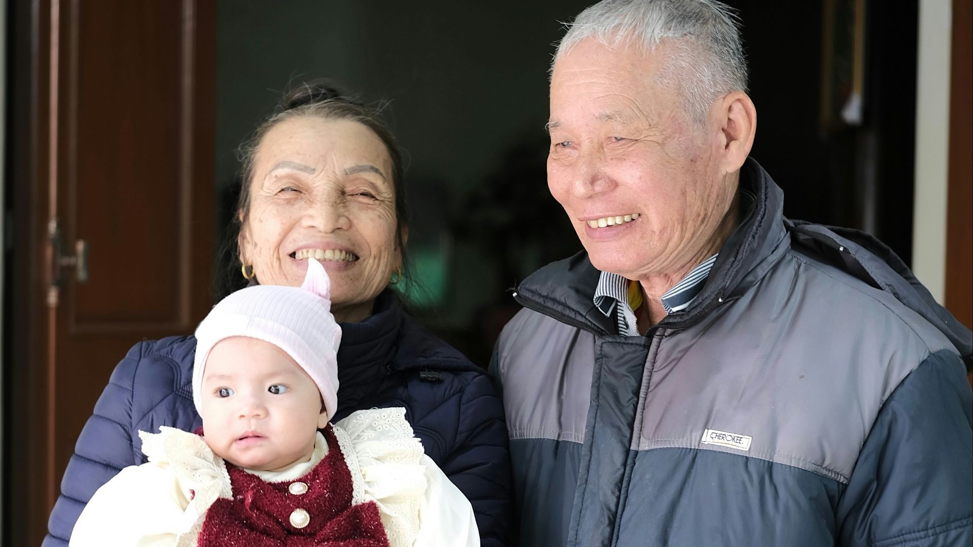 A man and a woman standing next to each other holding a baby