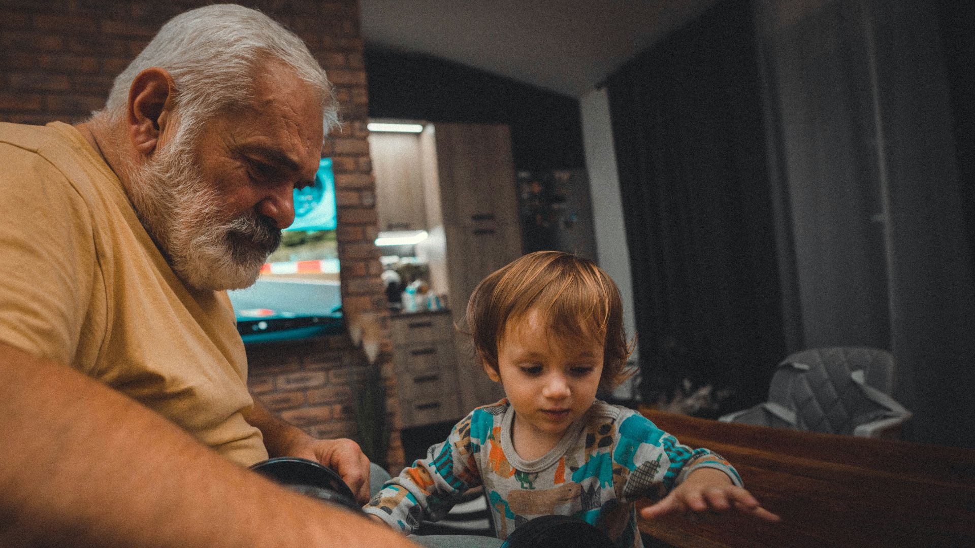 an older man and a young boy playing with a toy car