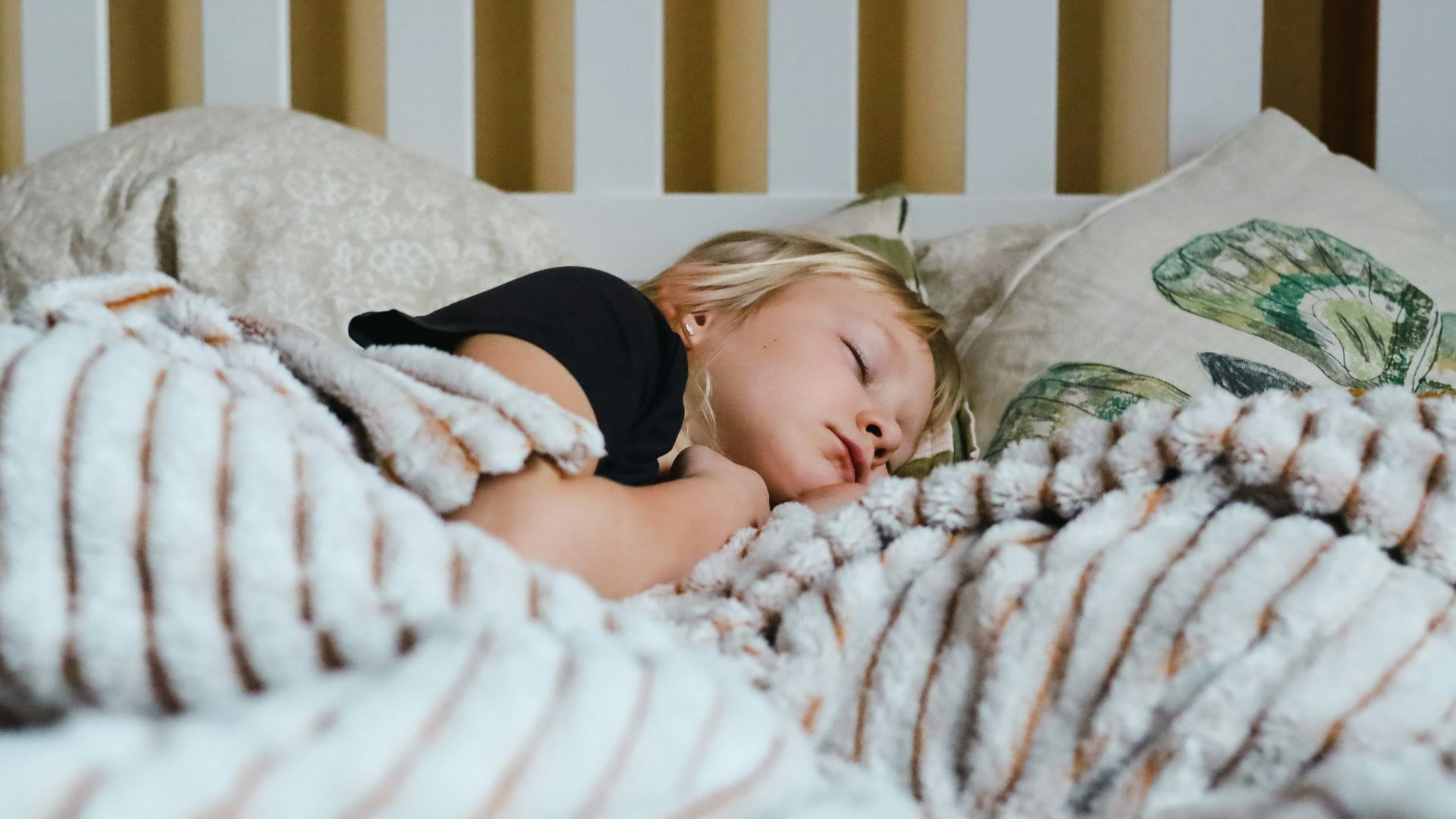 a little girl sleeping in a bed with a blanket