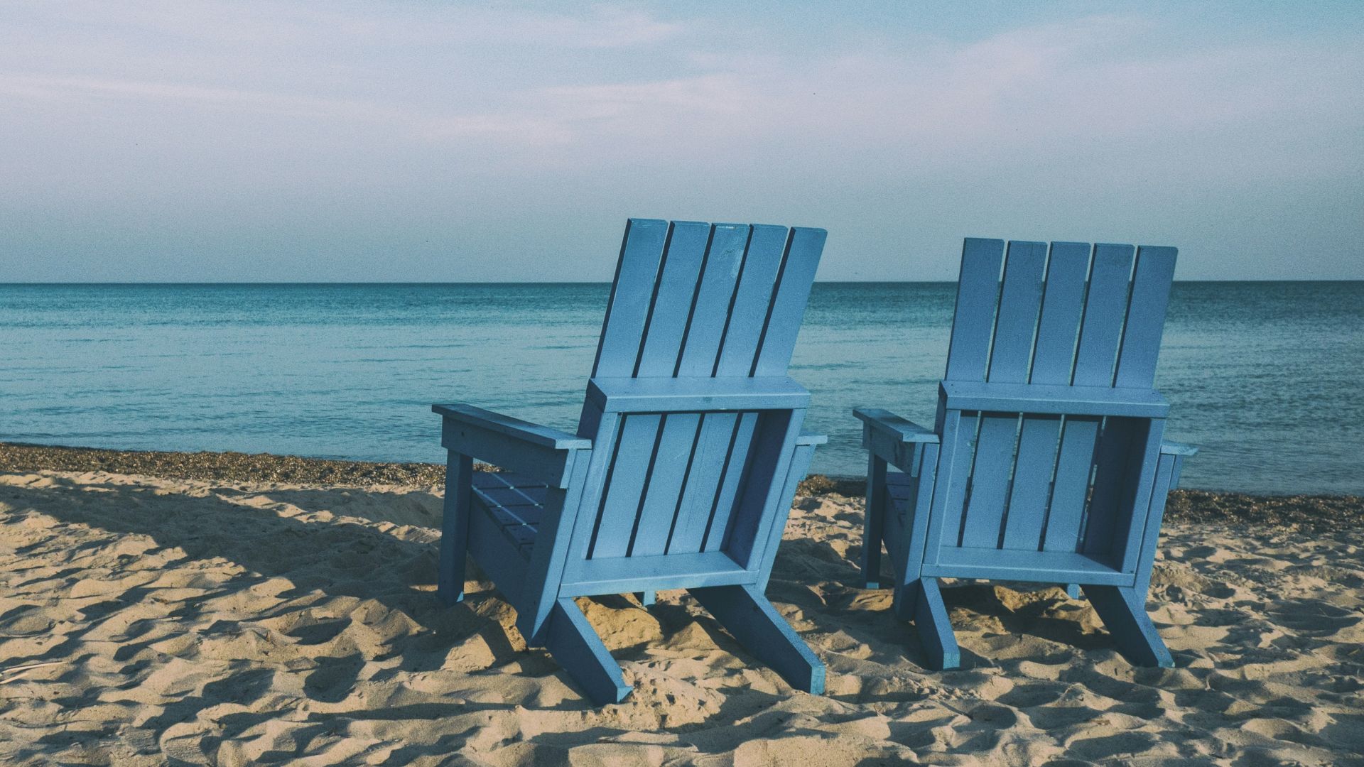 two blue beach chairs near body of water