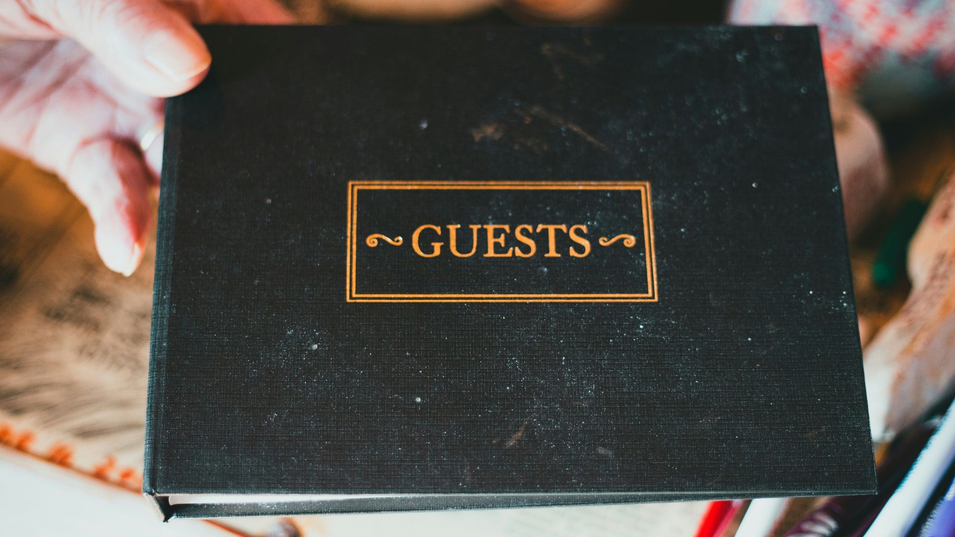 a person holding a black book with the word guests on it