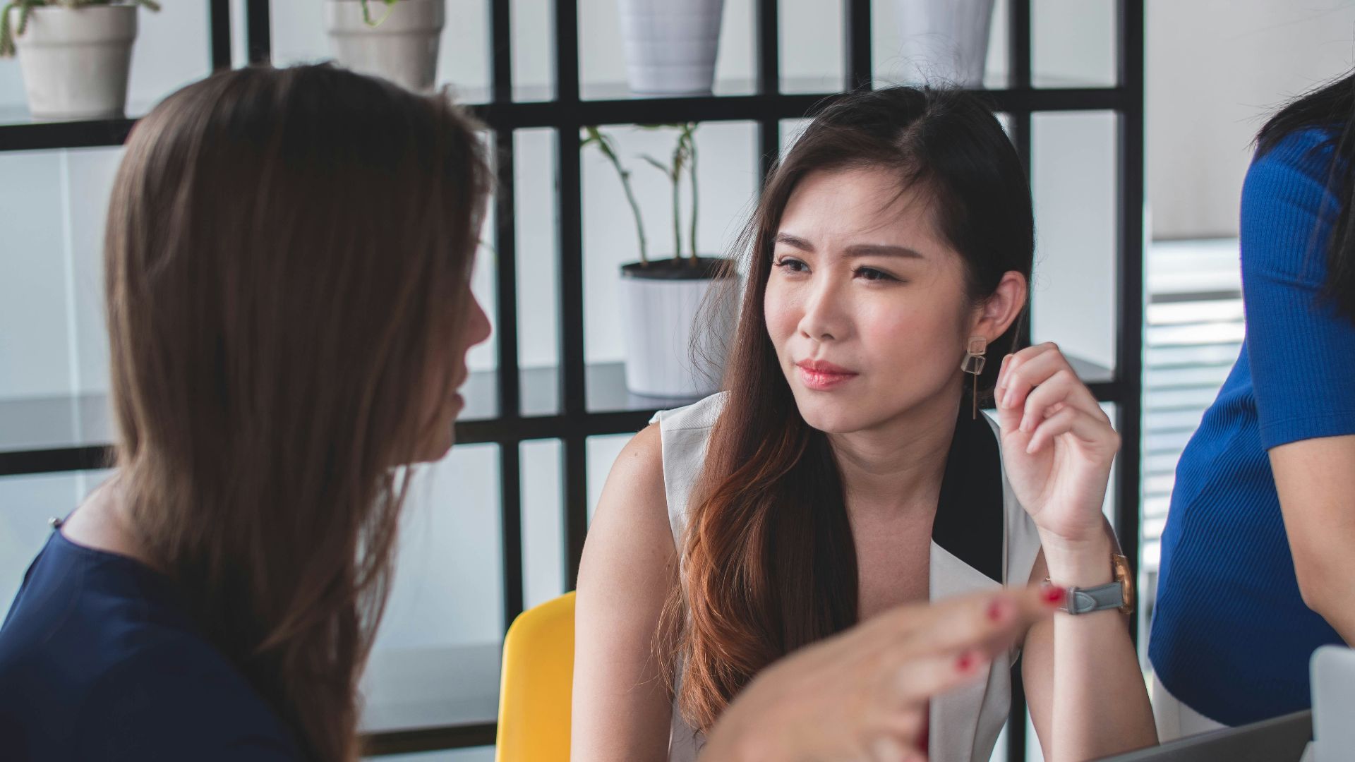 woman sitting on yellow armless chair near gray laptop computer