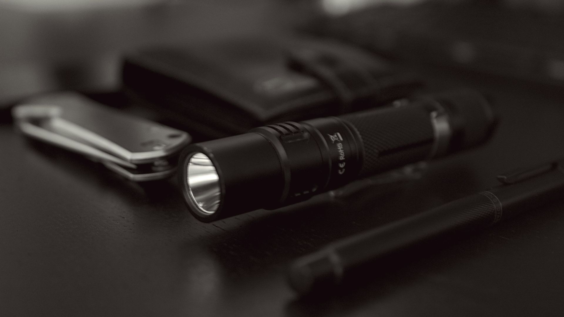 a black and white photo of a flashlight and a cell phone