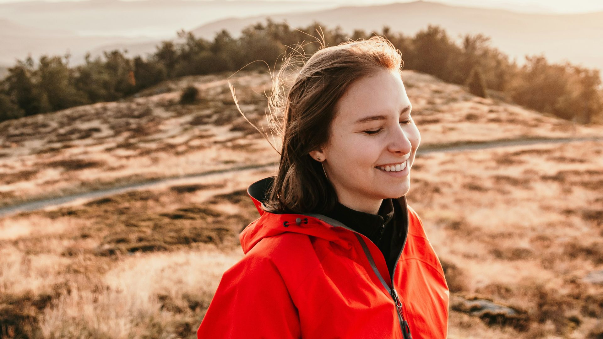 woman in red jacket standing on brown field during daytime