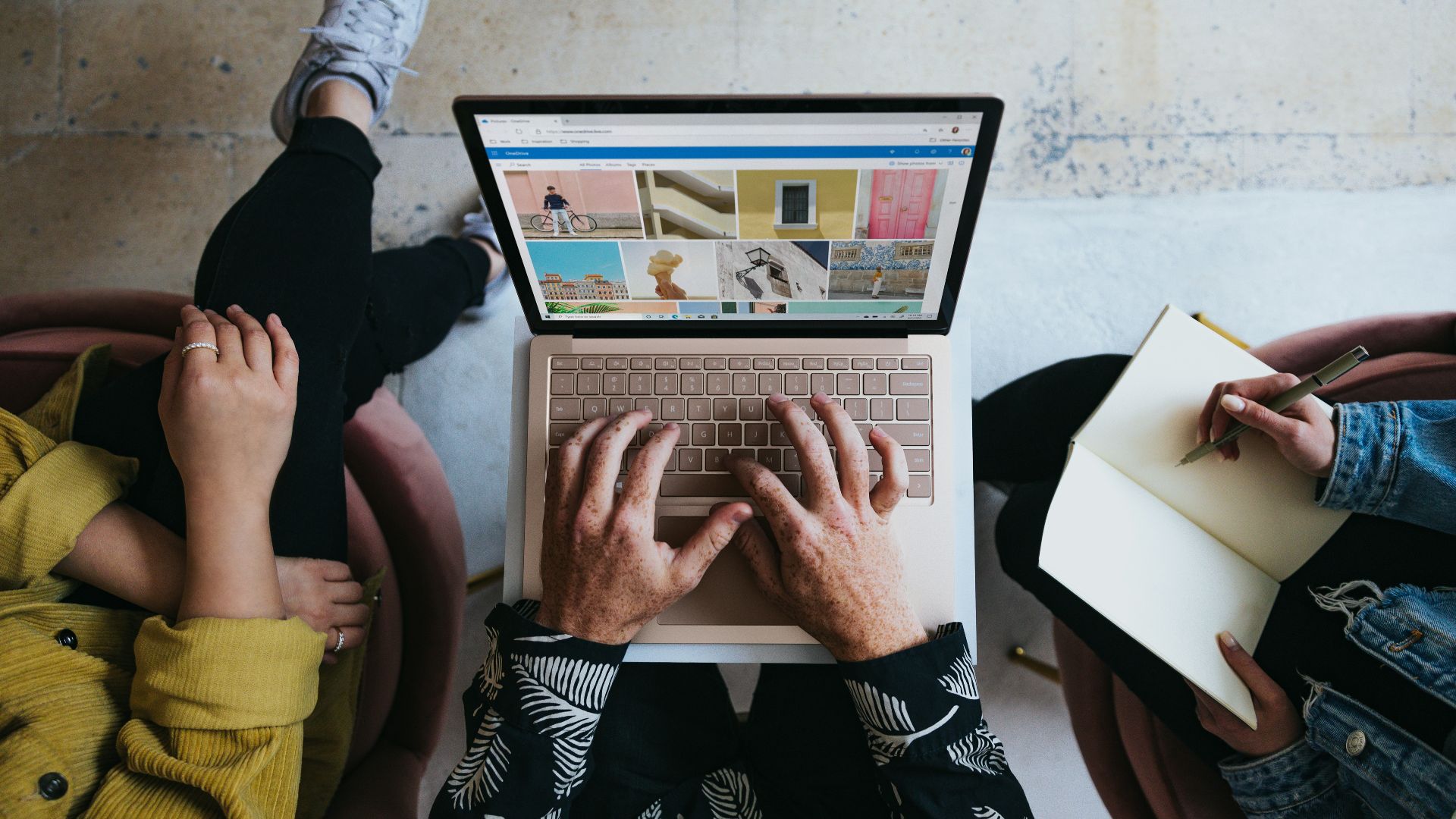 person using microsoft surface laptop on lap with two other people