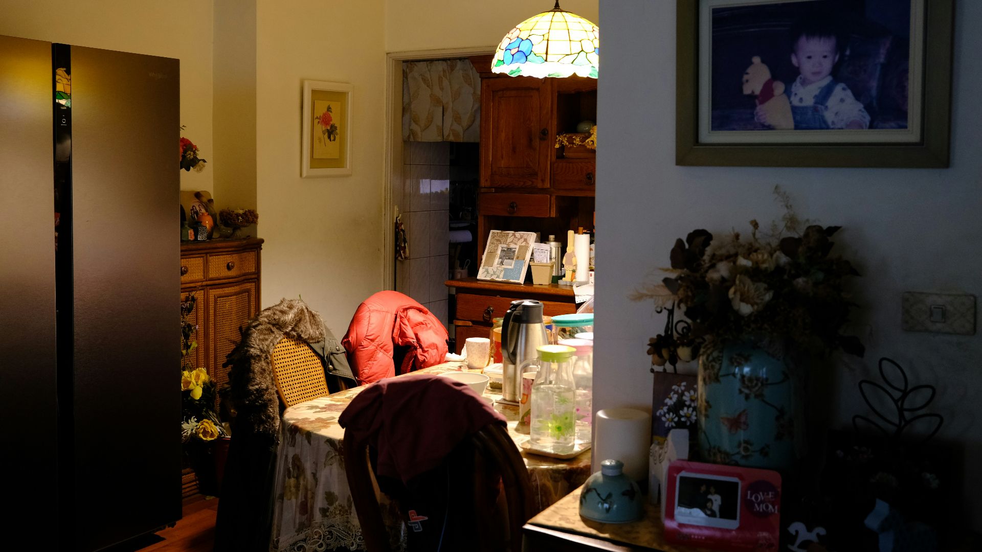 a living room with a table and a refrigerator