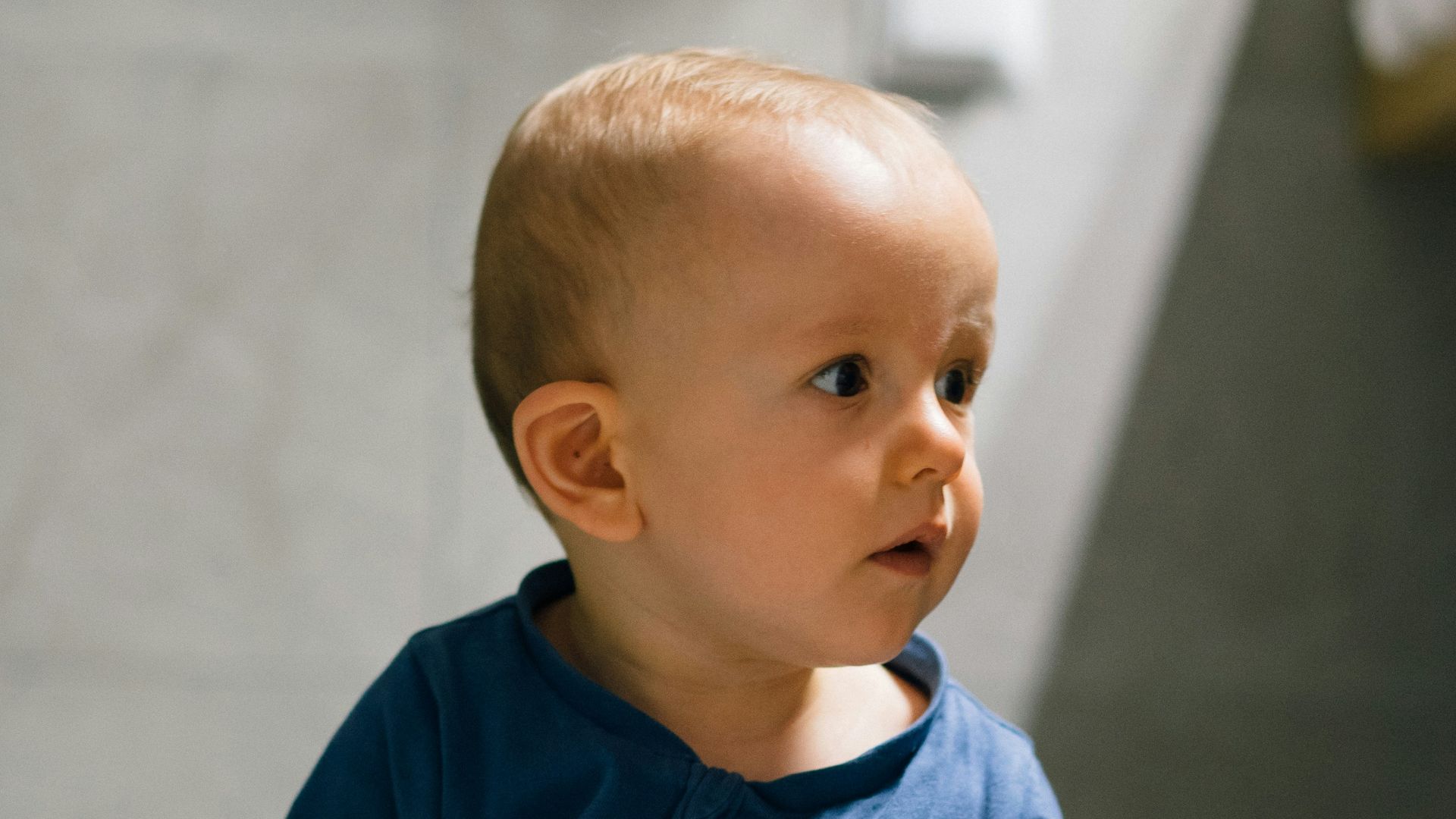 baby in blue long sleeve shirt and blue denim jeans sitting on floor