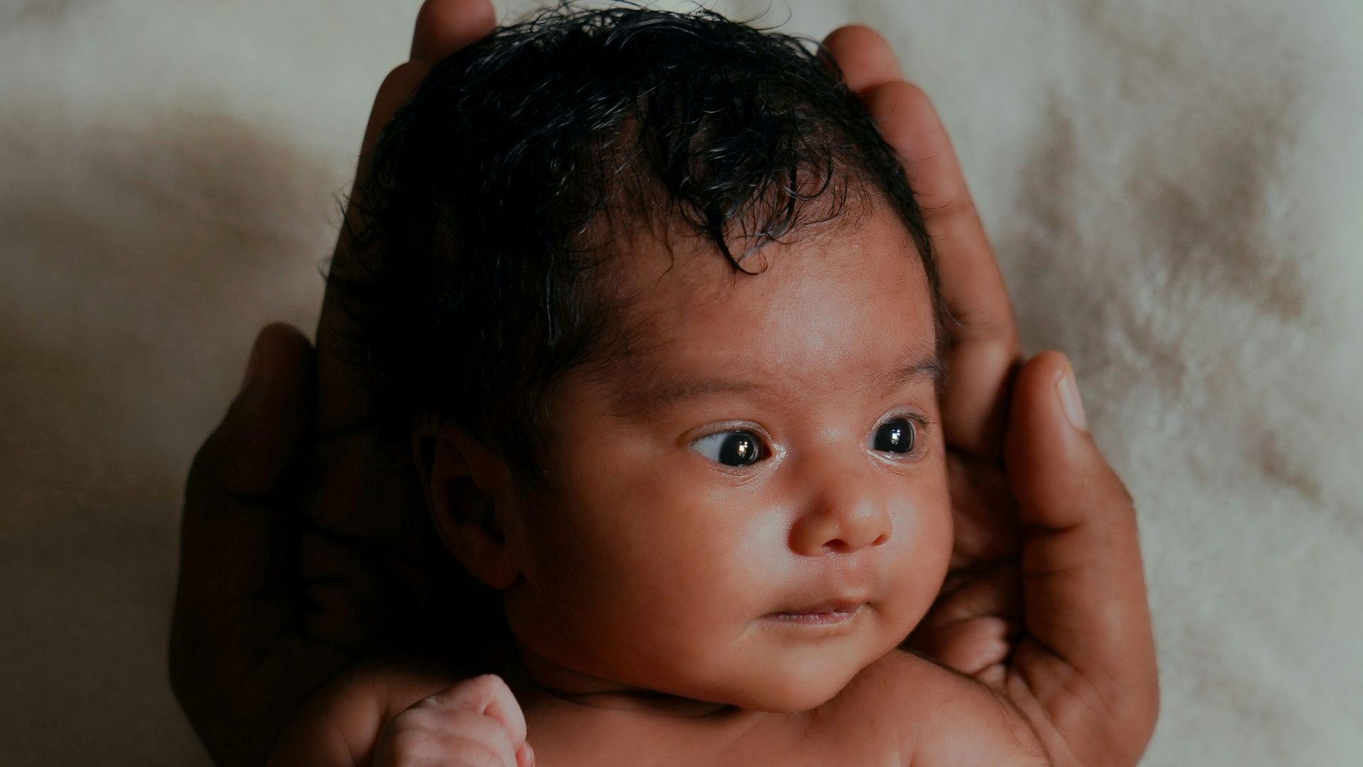 Newborn baby held gently in caring hands