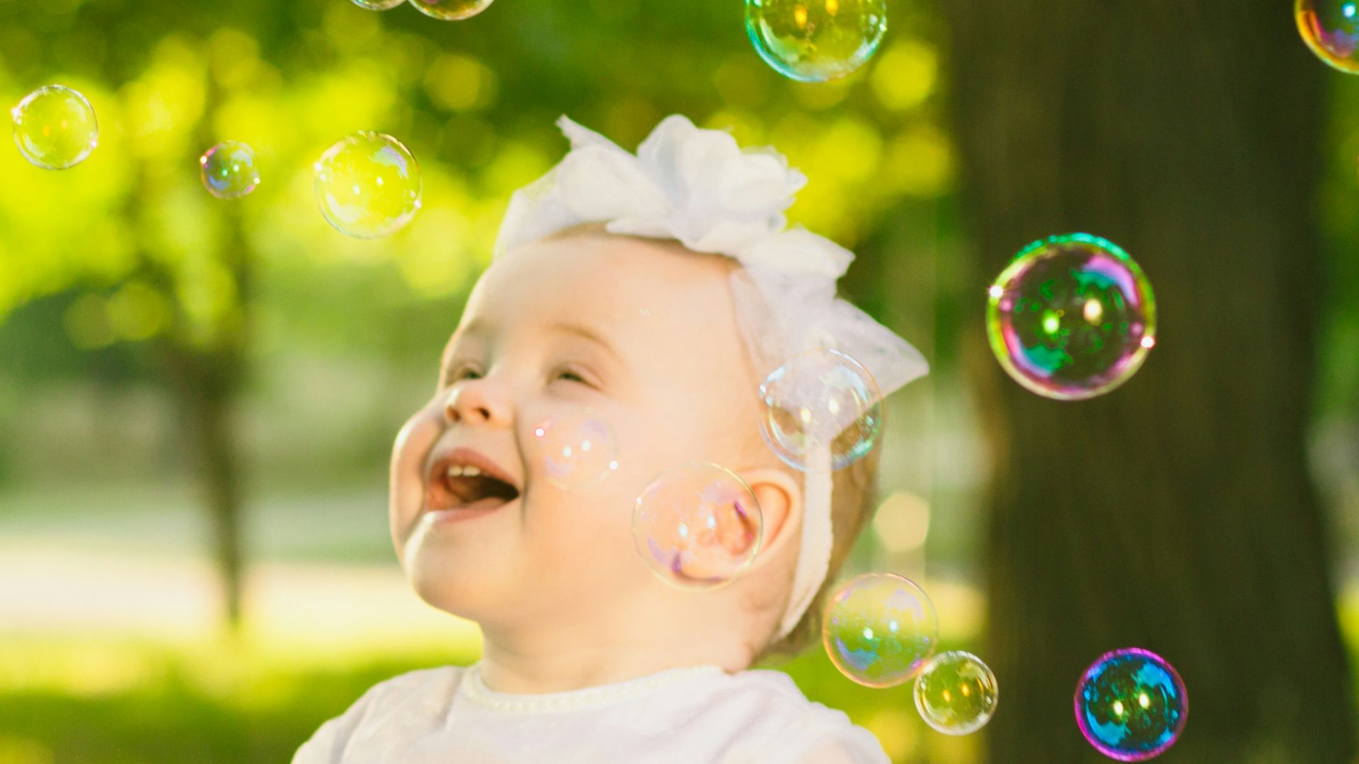 a baby girl in a white dress sitting in the grass