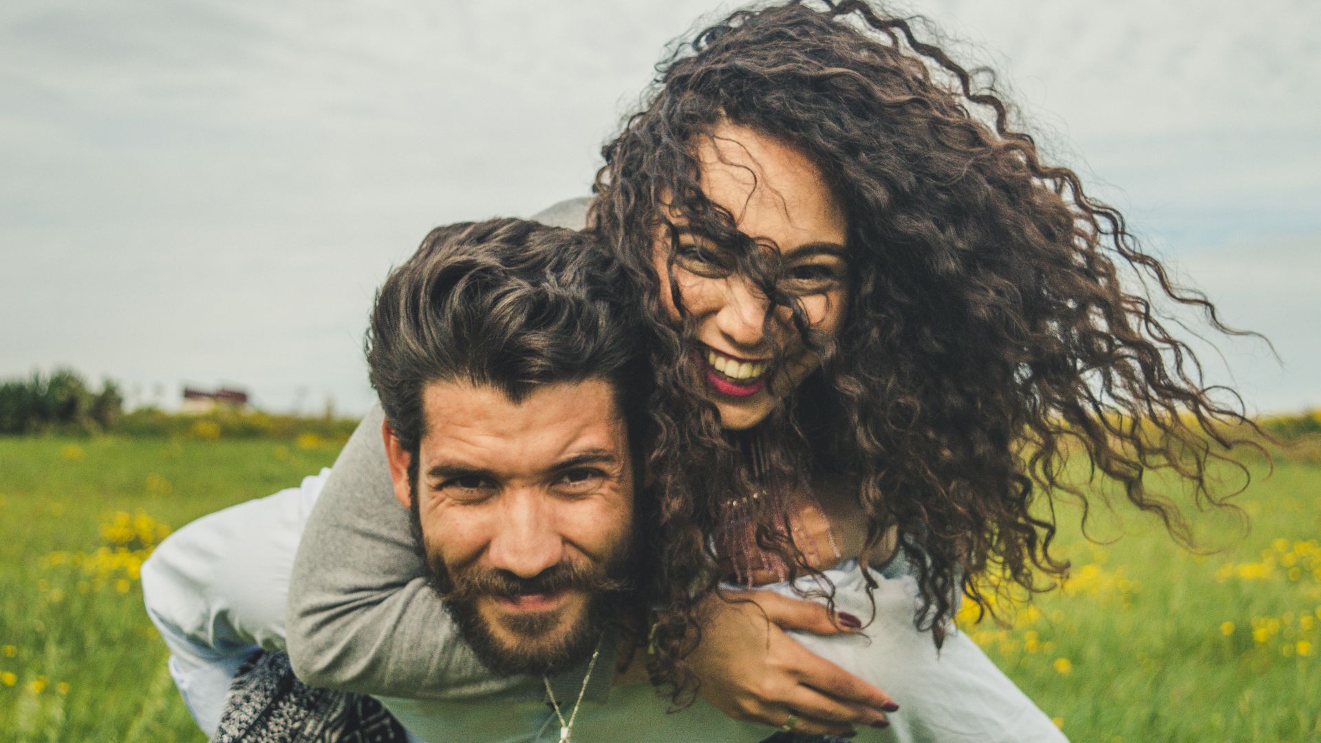 woman riding on man's back on green field