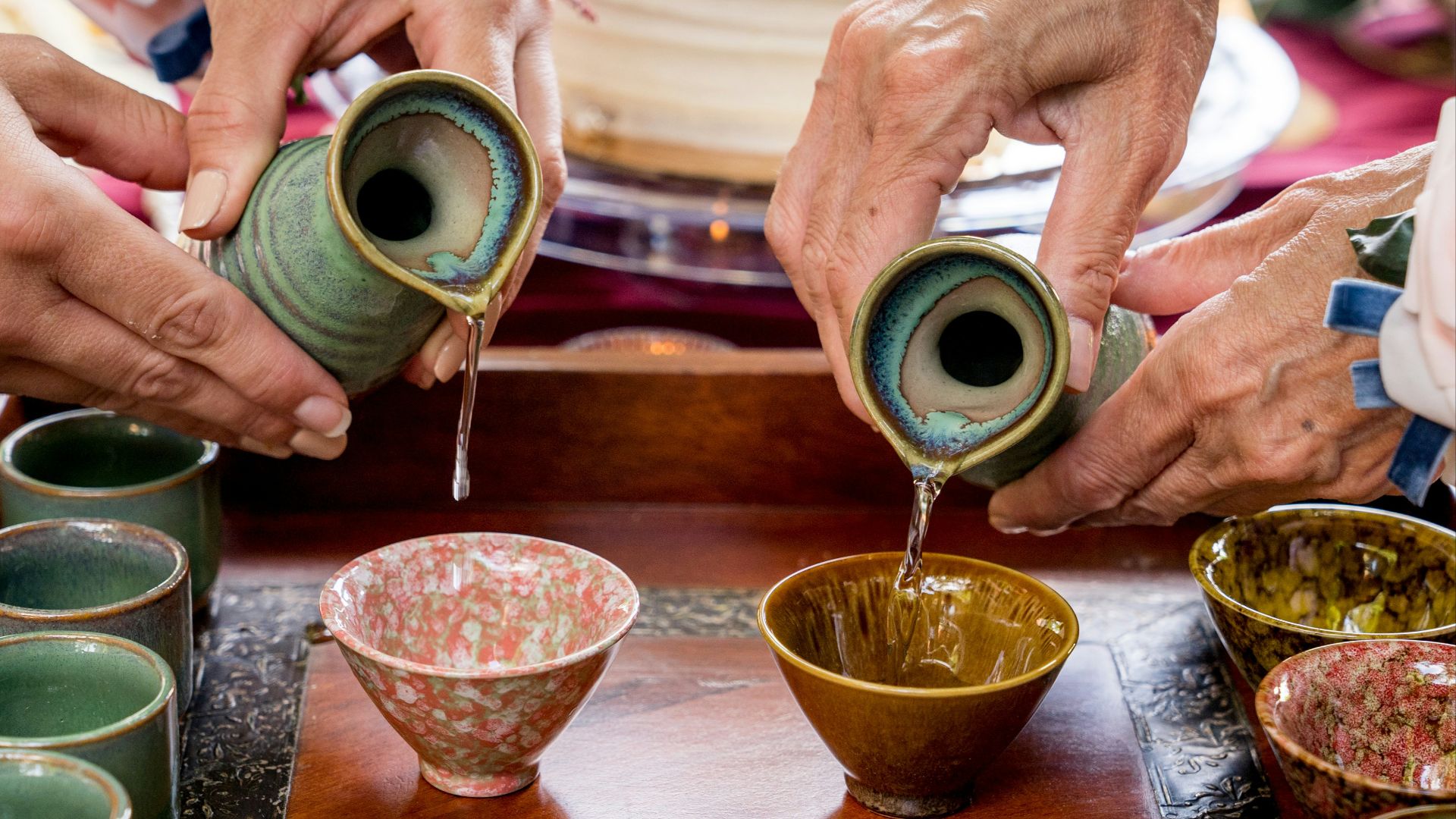a group of people pouring liquid into small cups