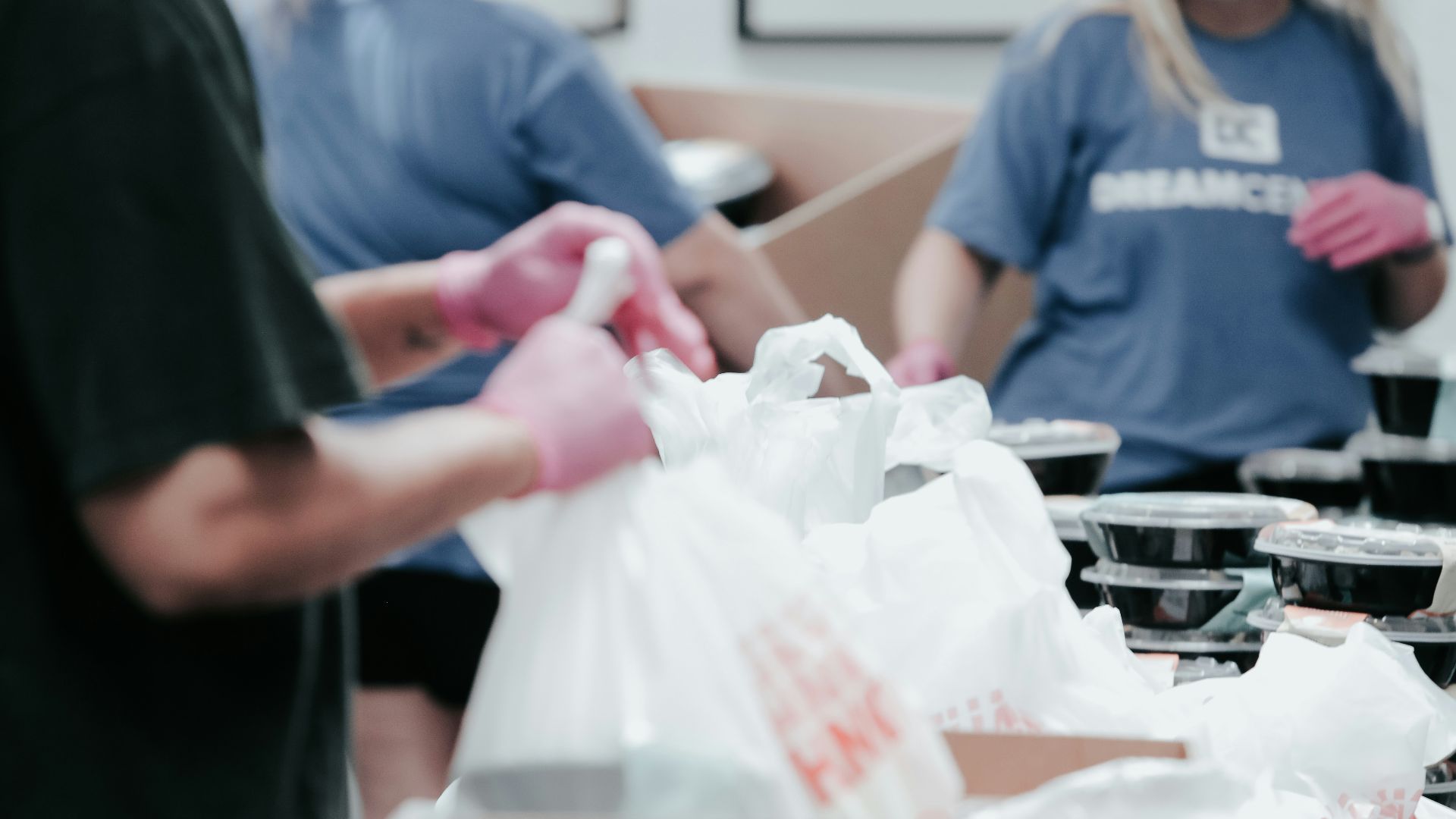 person in blue crew neck t-shirt holding white plastic bag