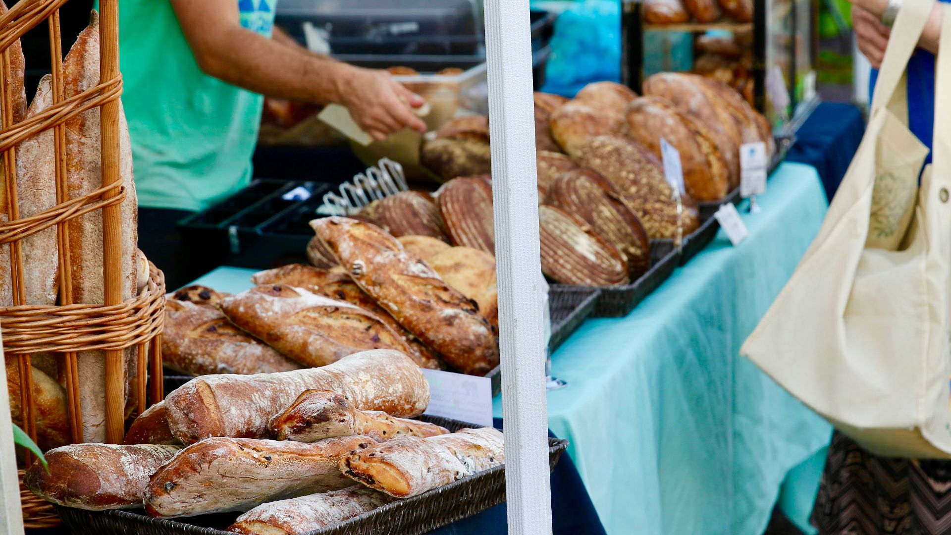 person carrying beige tote bag in front of food stall at daytime