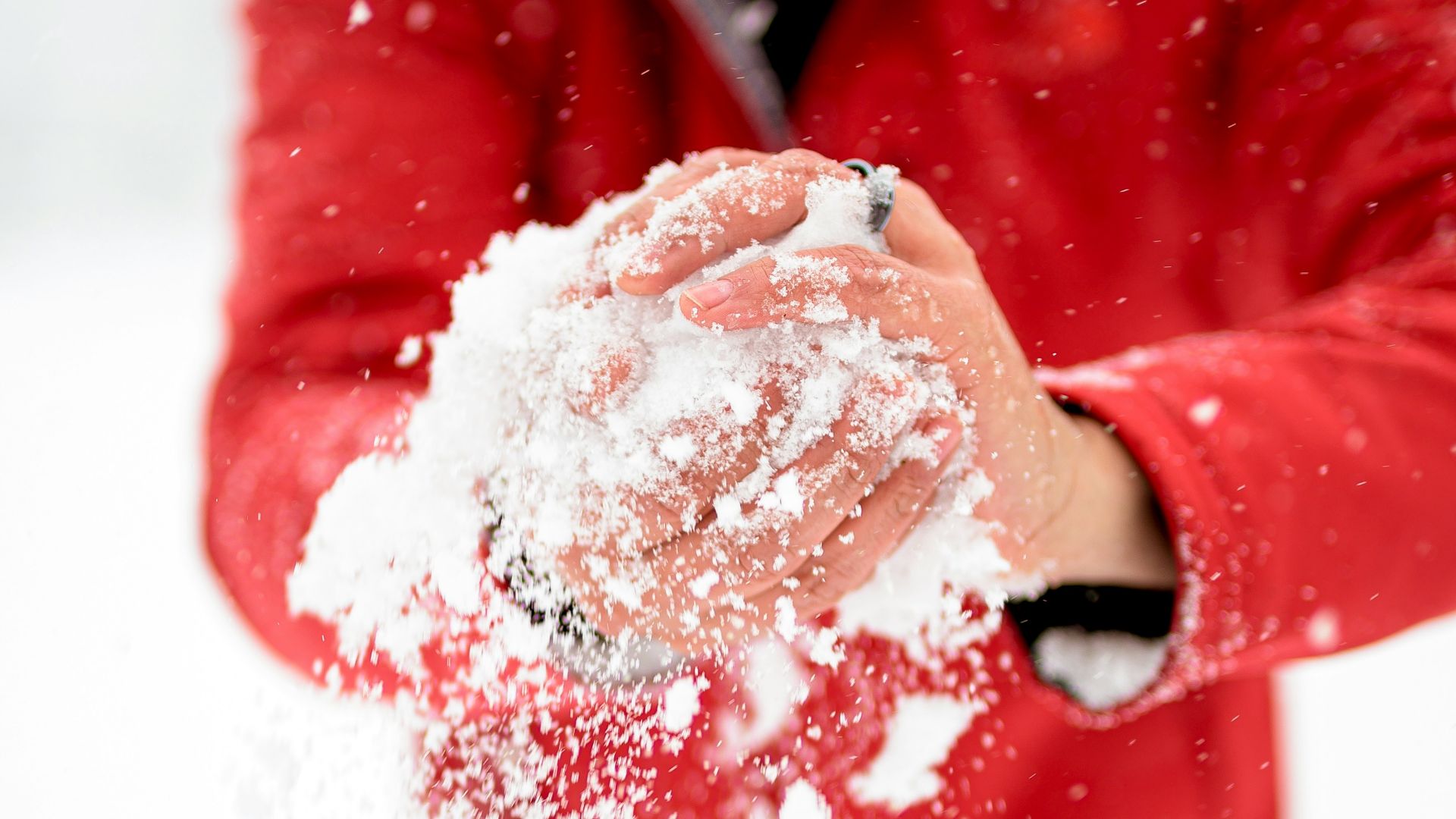 a man in a red jacket throwing snow in the air