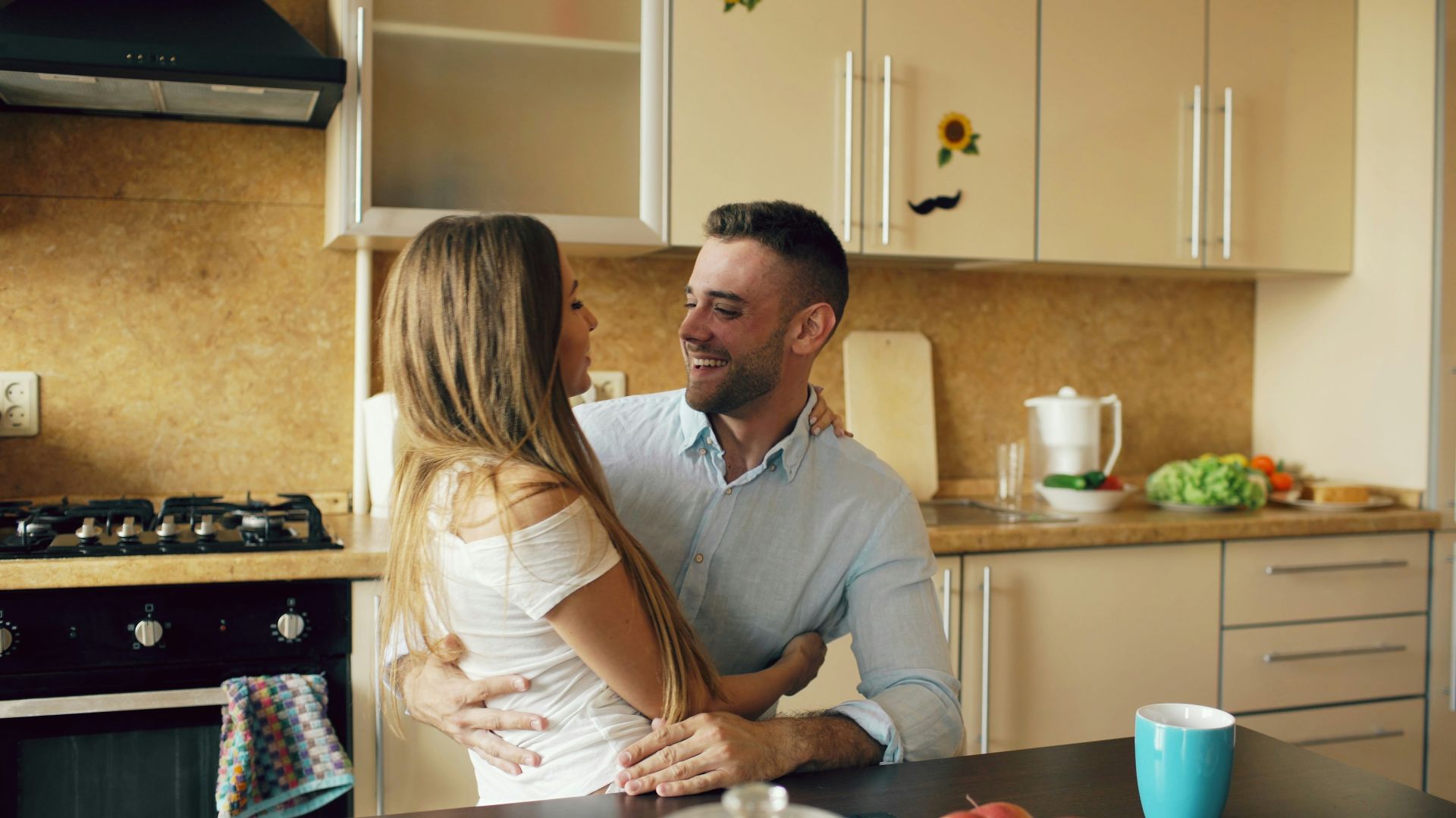 Couple embracing in a modern kitchen.