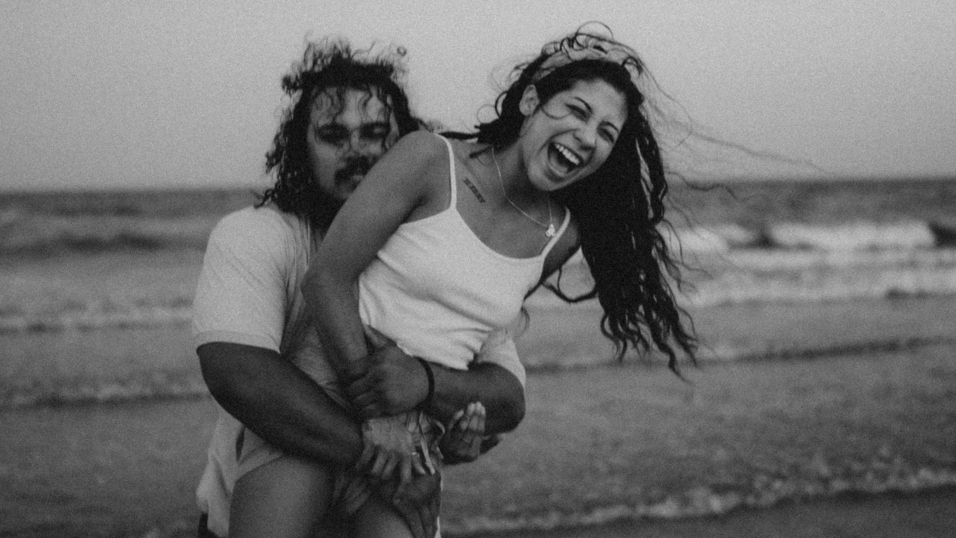 a man and woman posing on a beach