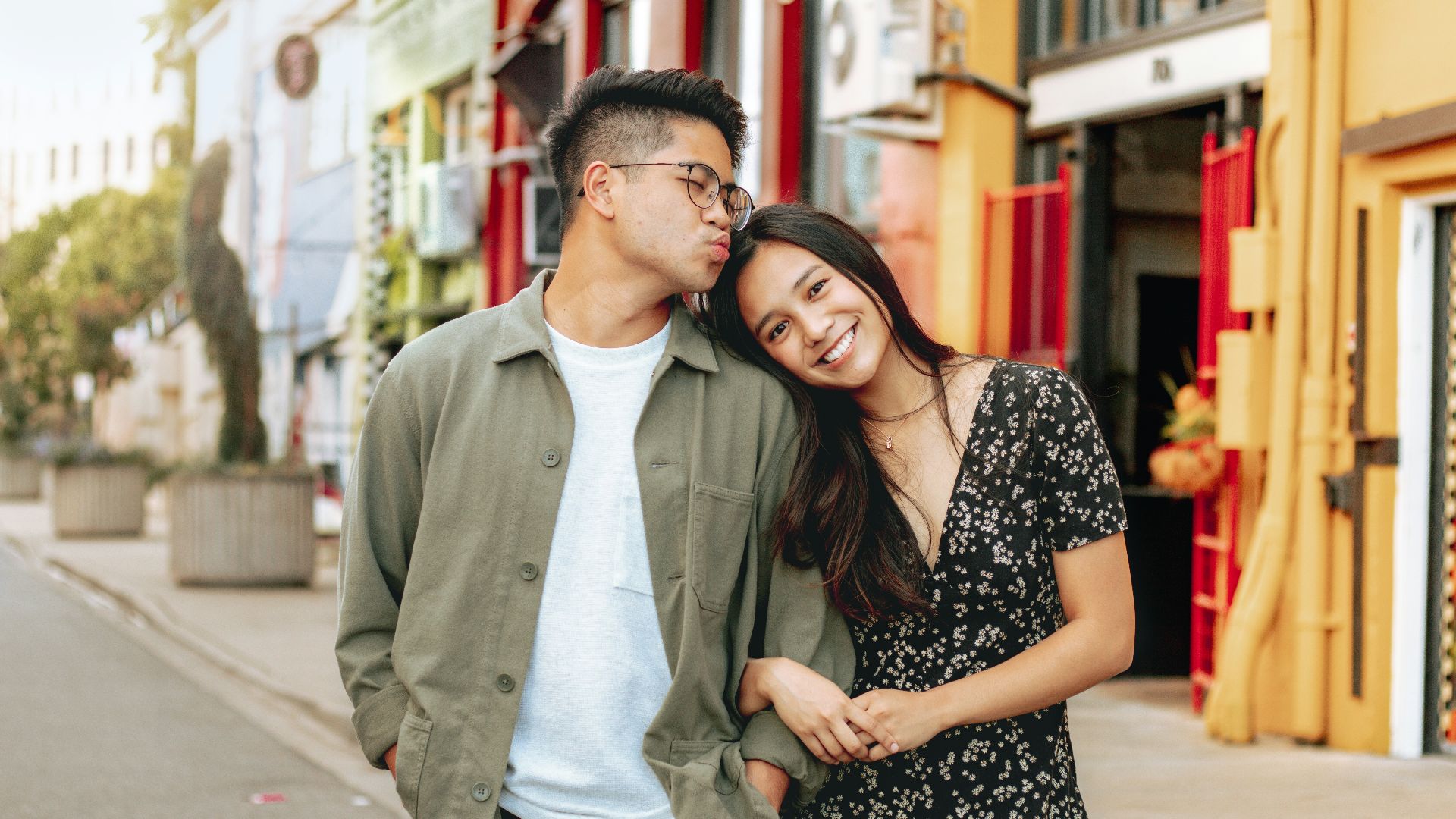 man in gray zip up jacket standing beside woman in black and white floral dress
