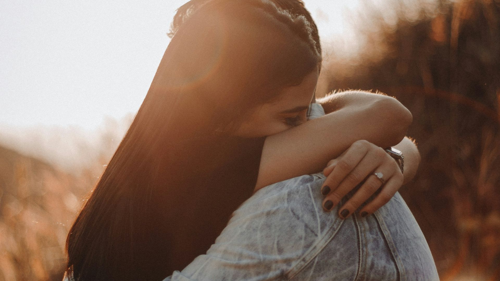 woman in black long sleeve shirt and blue denim jeans covering her face with her hand