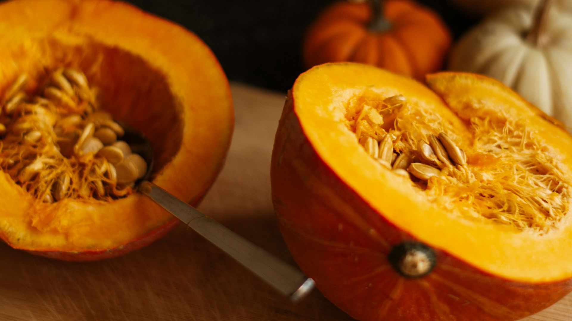 a cutting board topped with a cut in half pumpkin