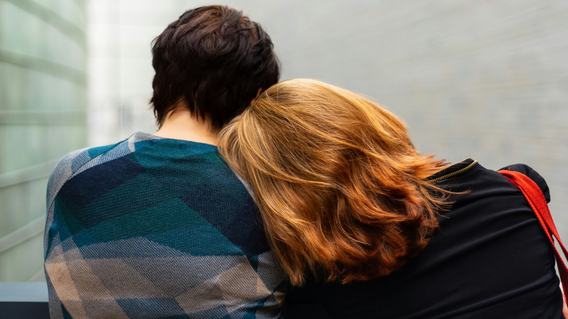 a woman rests her head on another person's shoulder