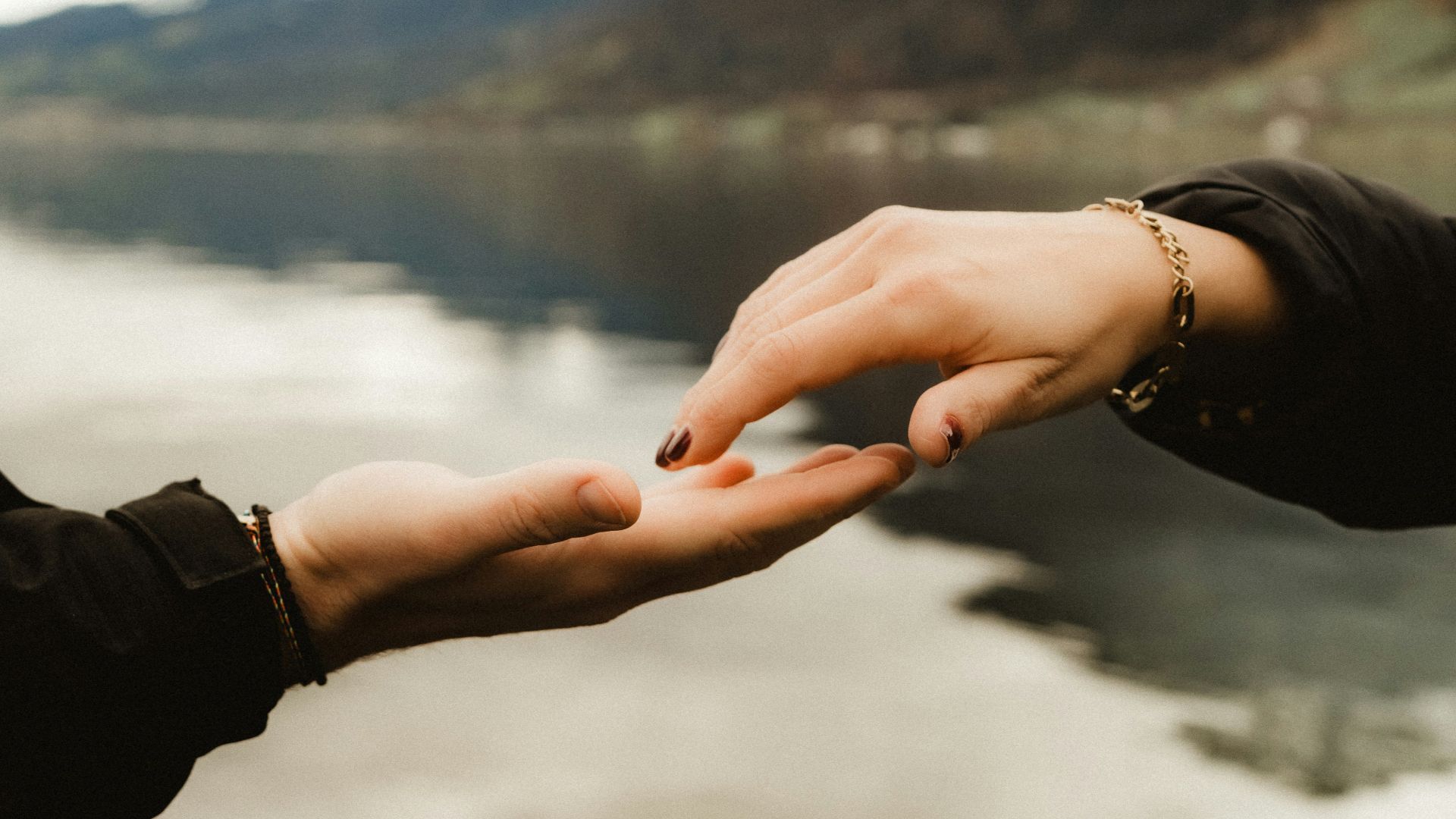 two people holding hands over a body of water