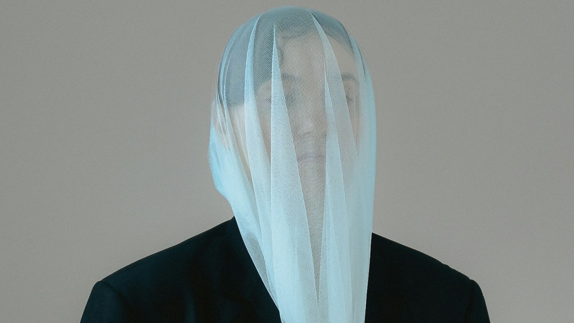 a man in a suit with a veil on his head