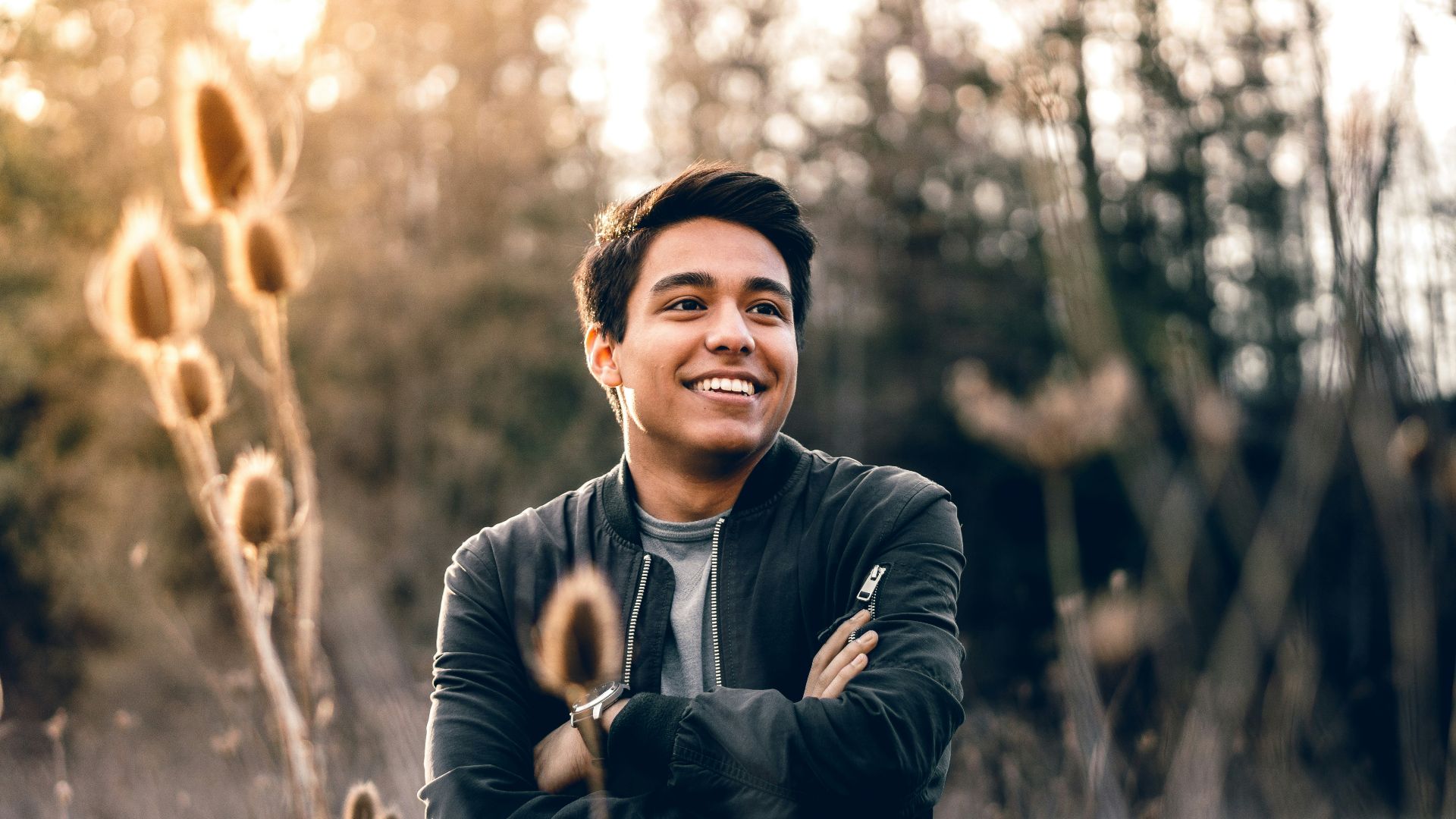 smiling man standing near green trees