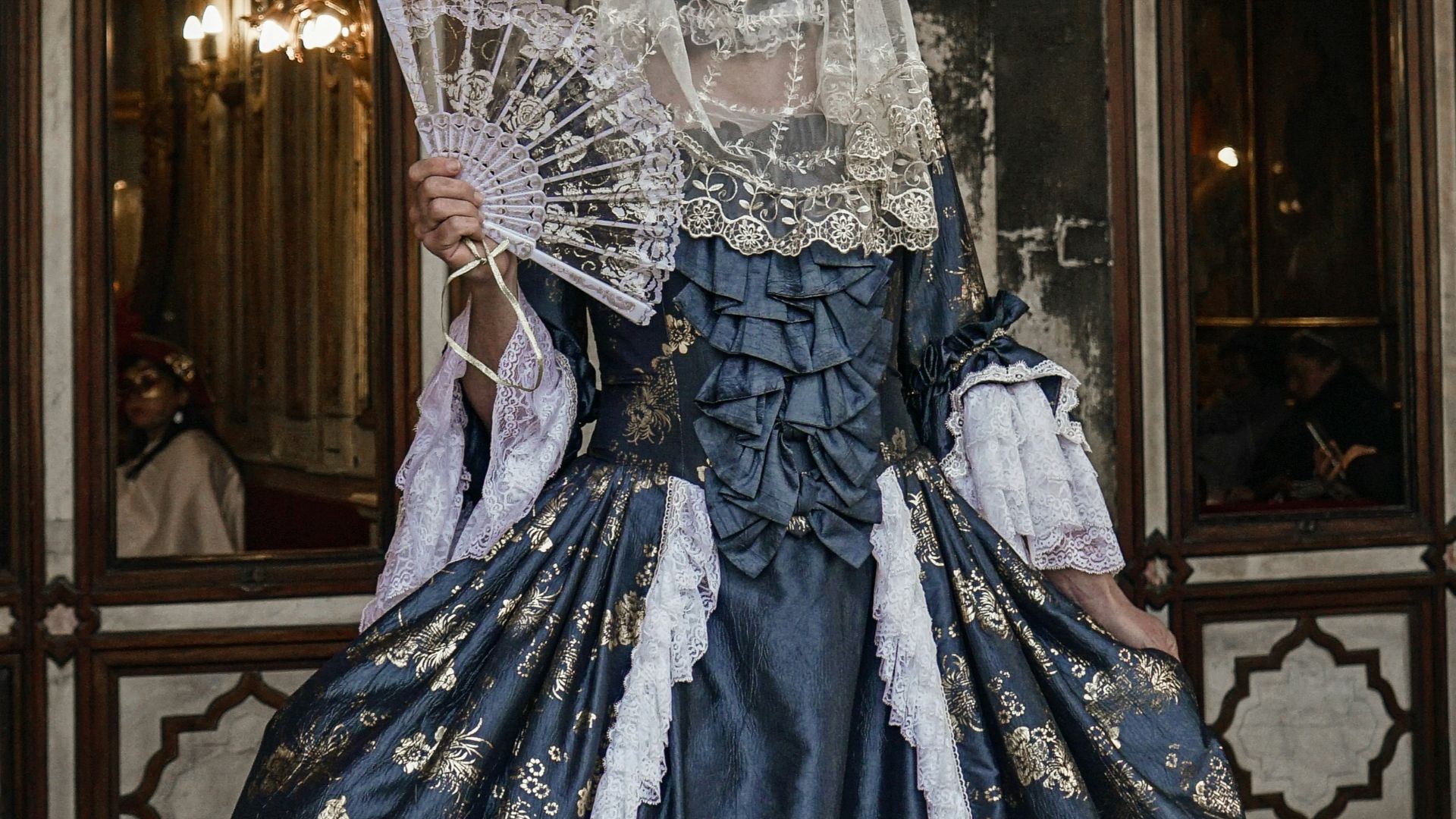a woman in a blue and white dress standing in front of a building