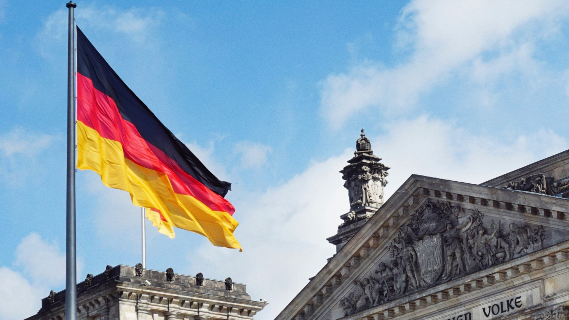 white concrete building with flags on top under blue sky during daytime