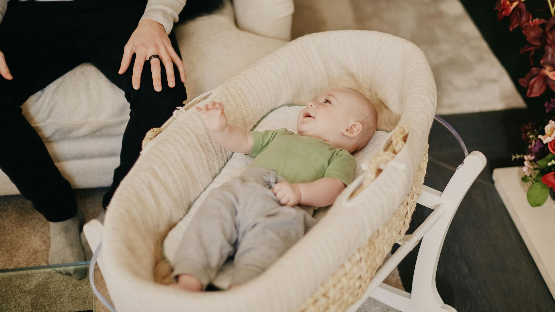 baby in green onesie lying on white and brown crib