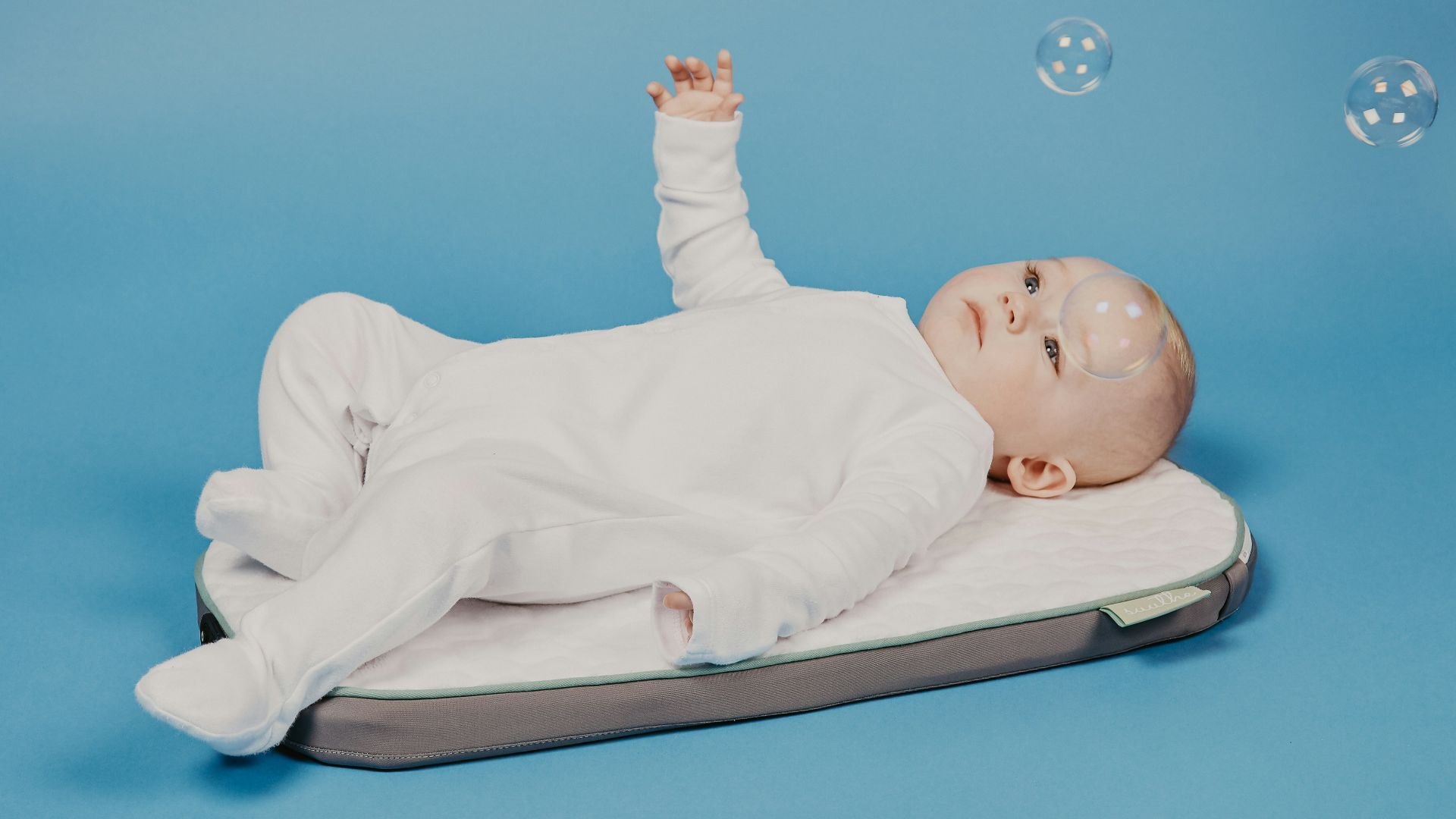 baby in white onesie lying on white bed