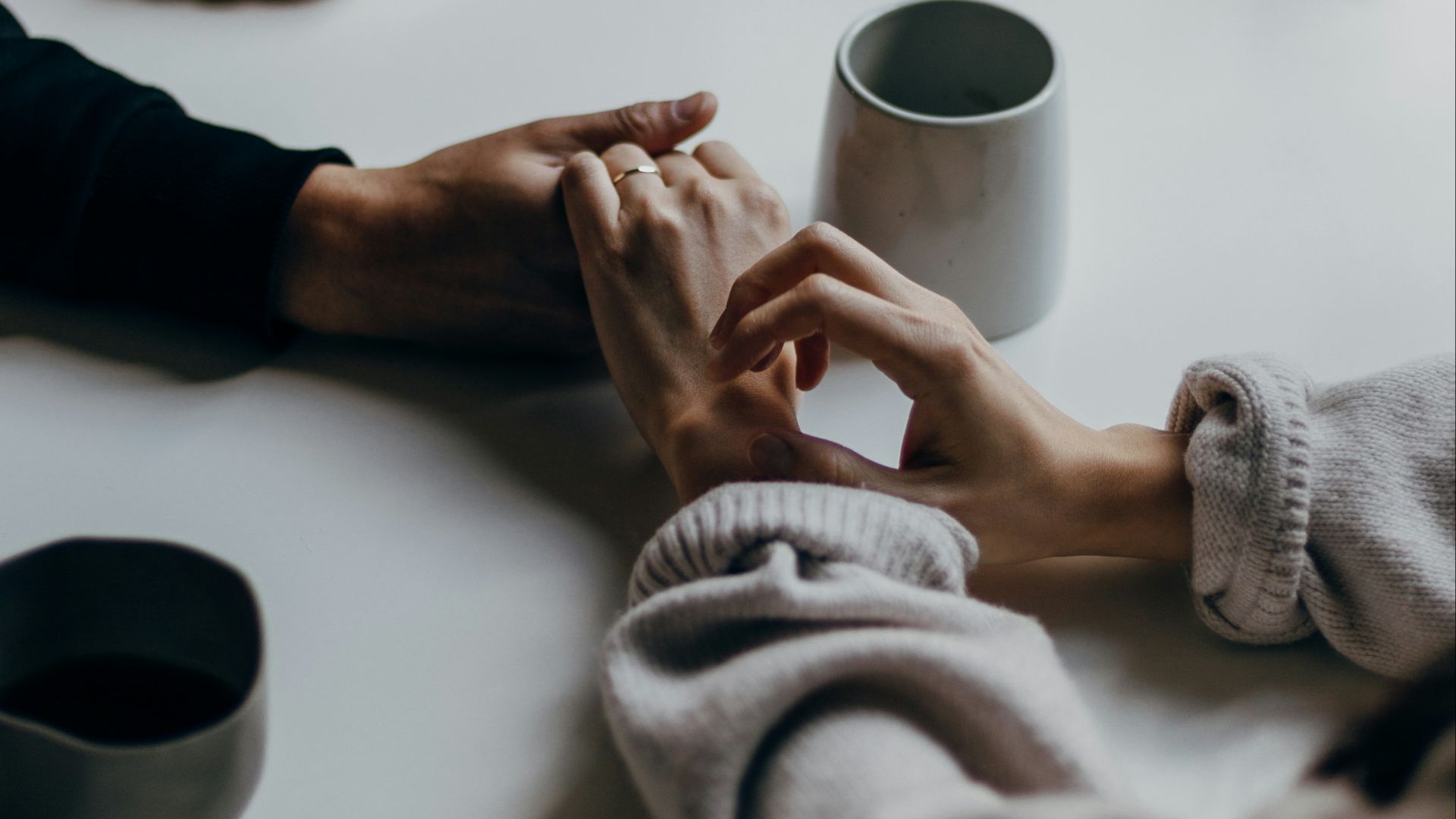 person in black long sleeve shirt holding white ceramic mug