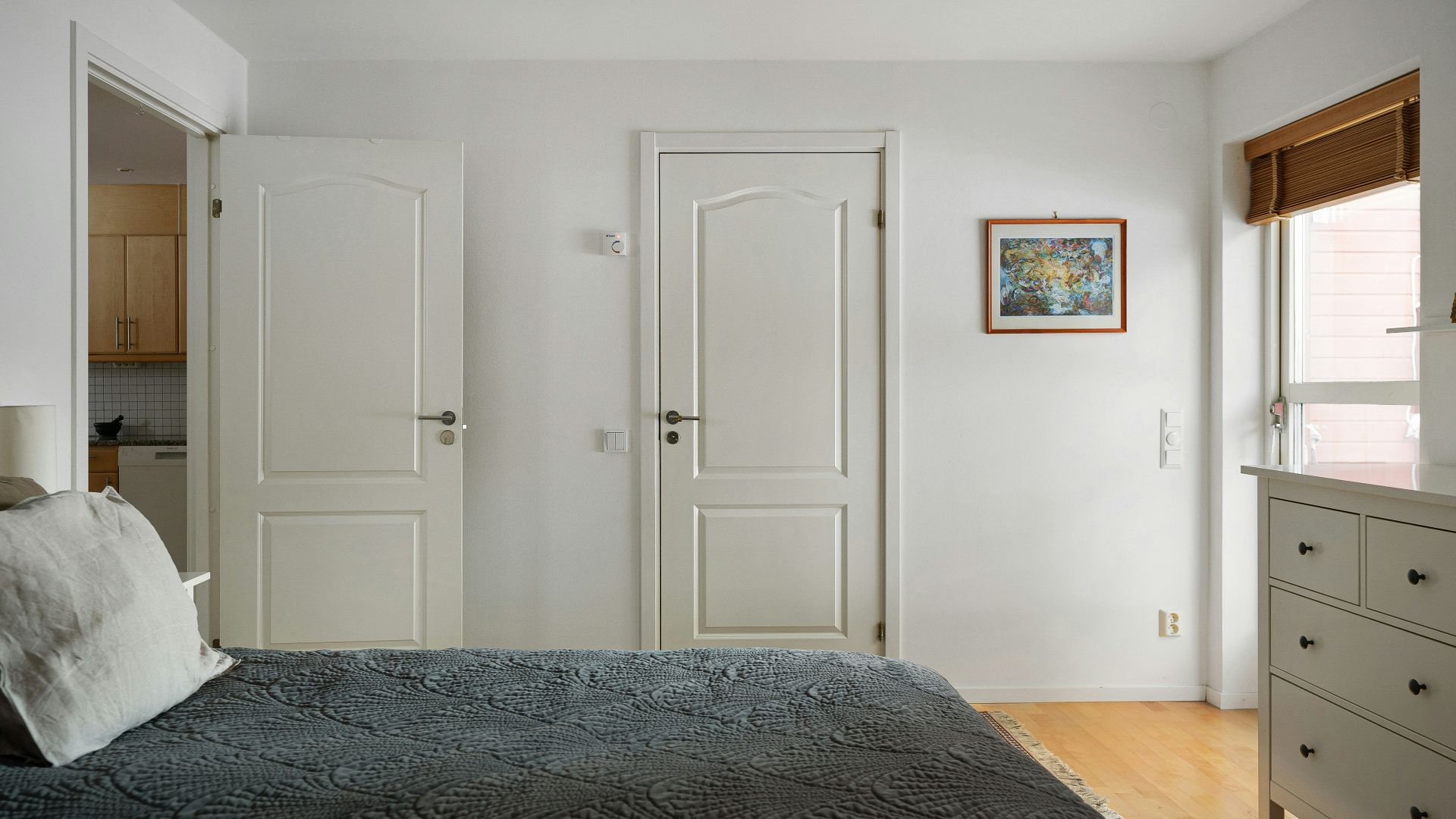 A bedroom with a bed, dresser, and mirror