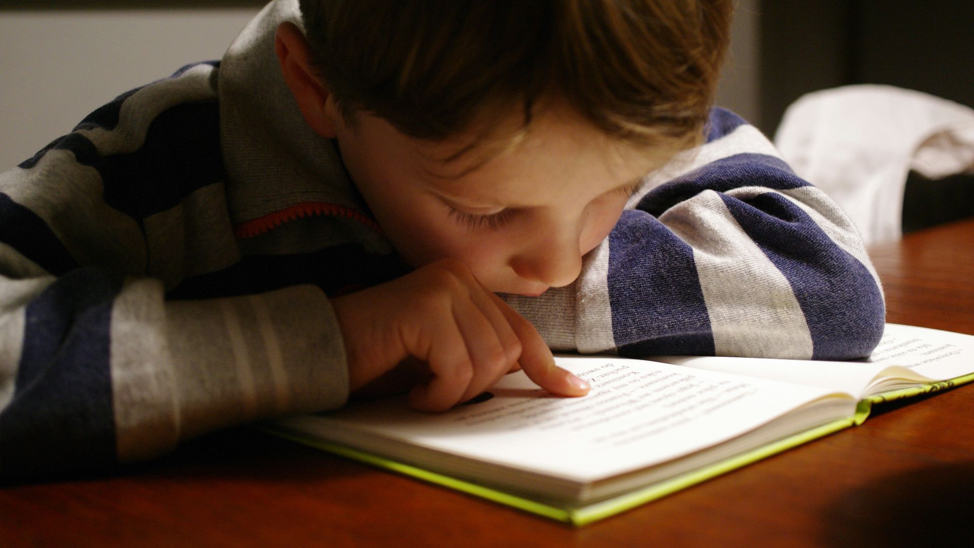 boy in gray and red hoodie reading book