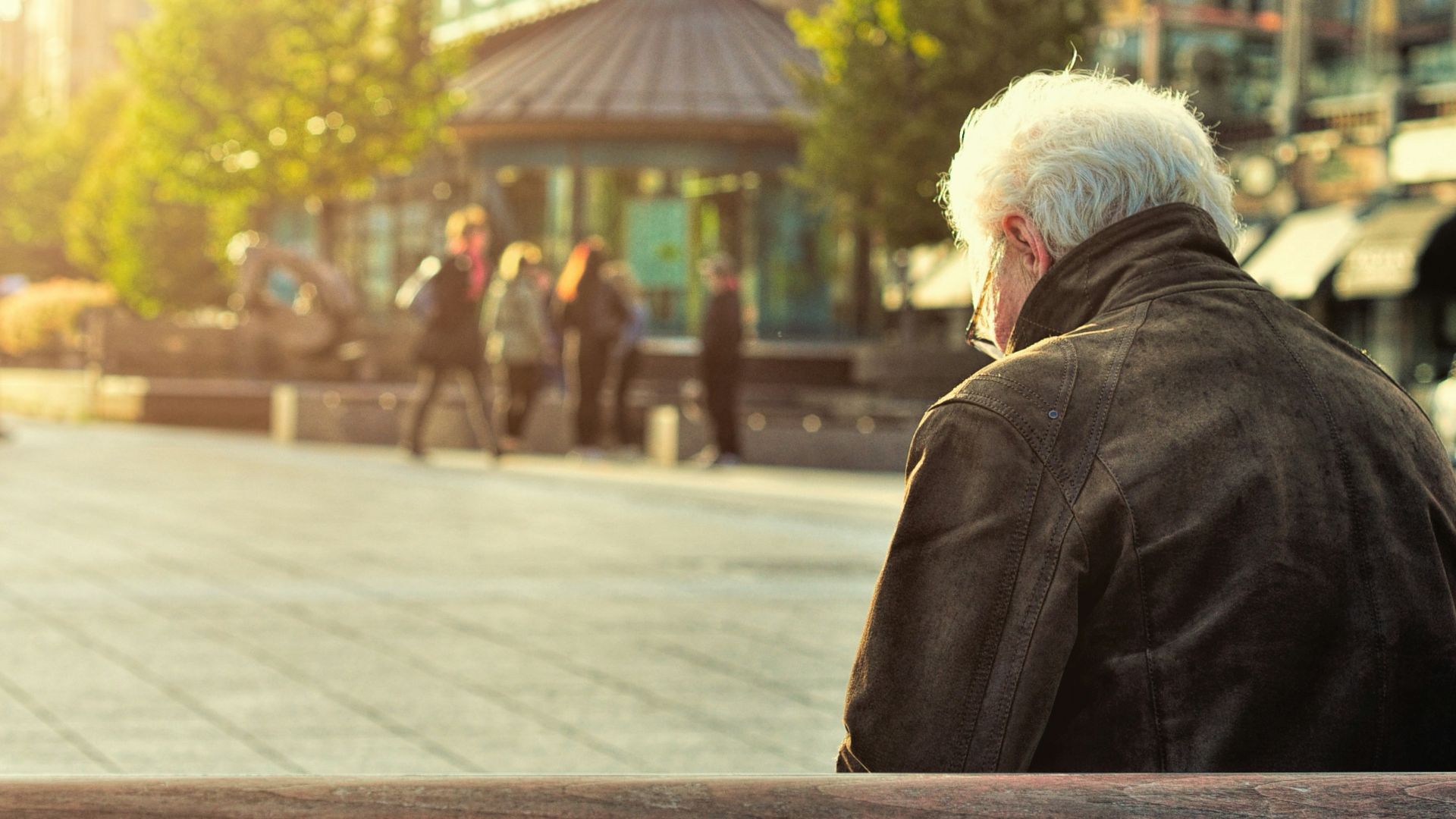 man sitting on brown wooden bench