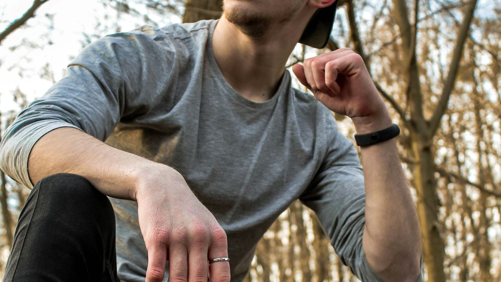 man in gray crew neck long sleeve shirt and black pants sitting on brown wooden log