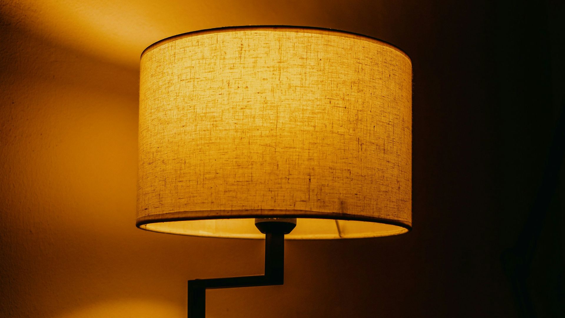 A modern desk lamp illuminates a dark room.