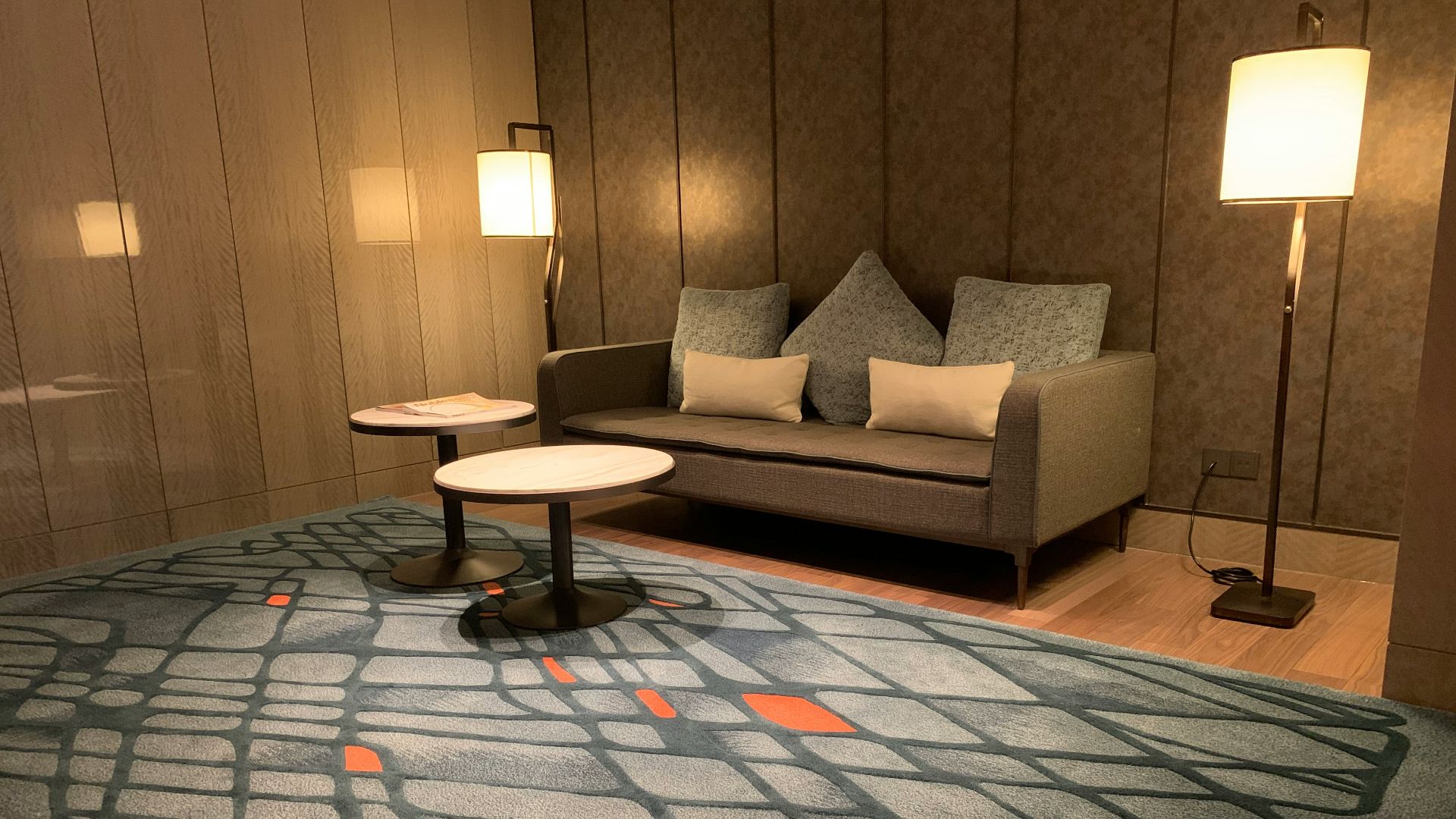 two round white tables beside sofa between floor lamps