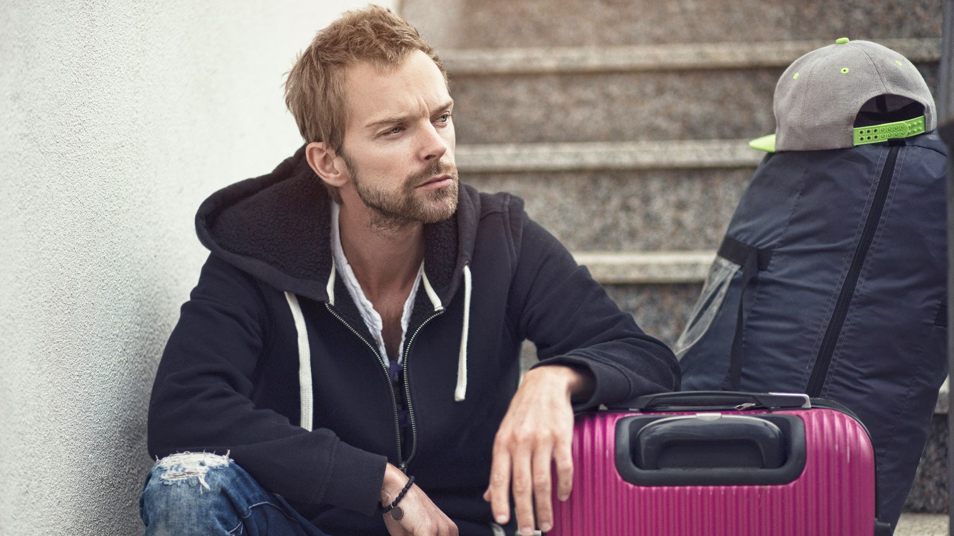 a man sitting next to a purple suitcase