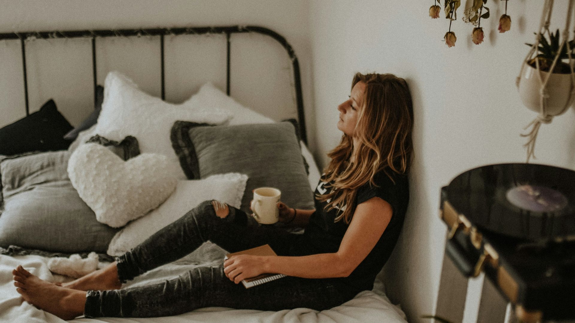 woman leaning on wall while sitting on bed