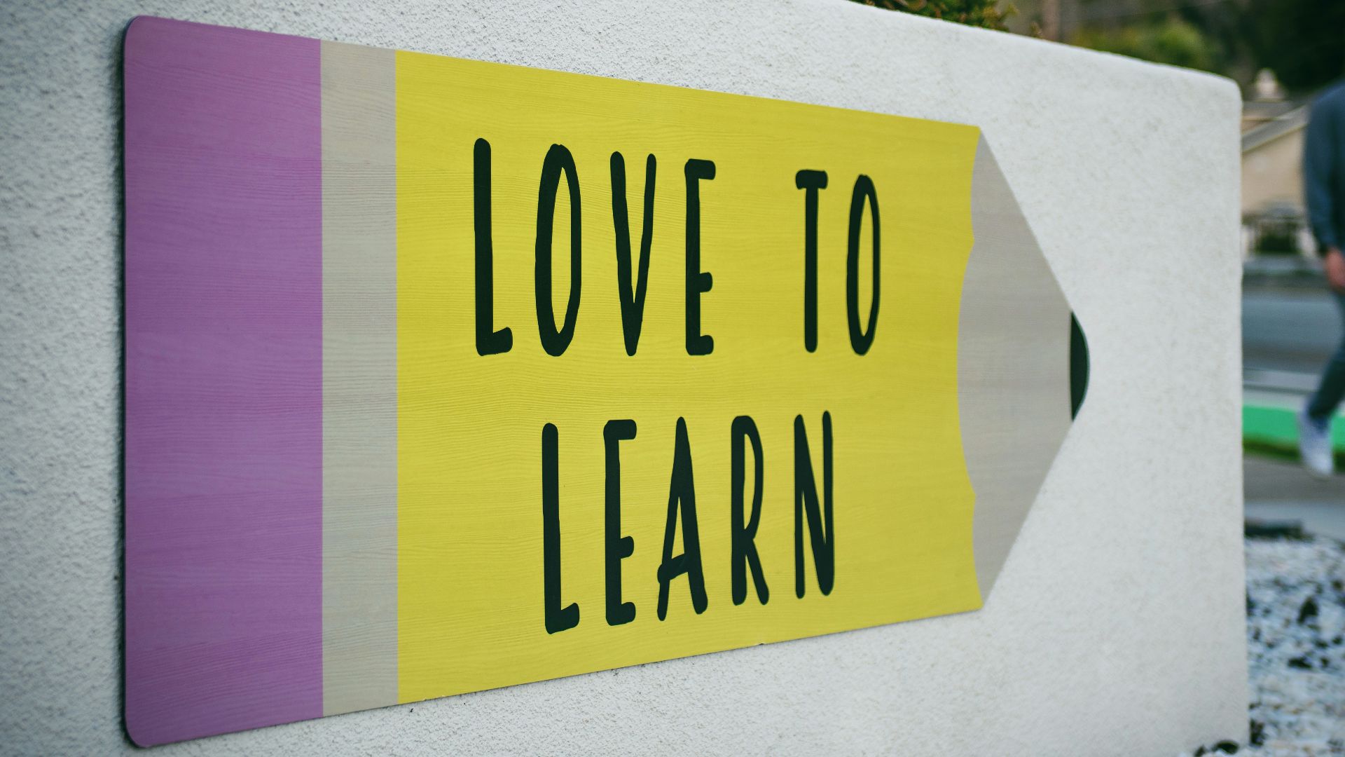 love to learn pencil signage on wall near walking man