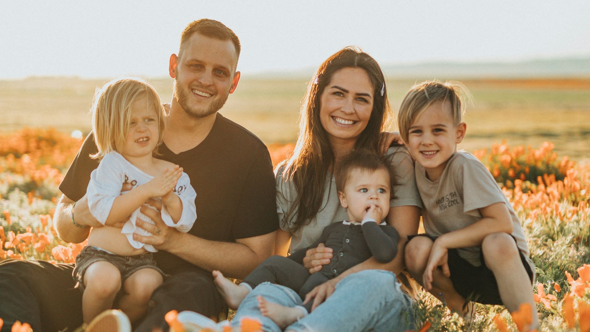3 women and 2 men sitting on green grass field during daytime