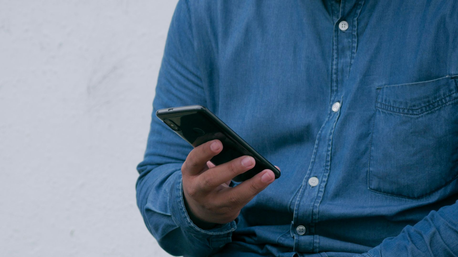 person in blue denim jacket holding smarthone