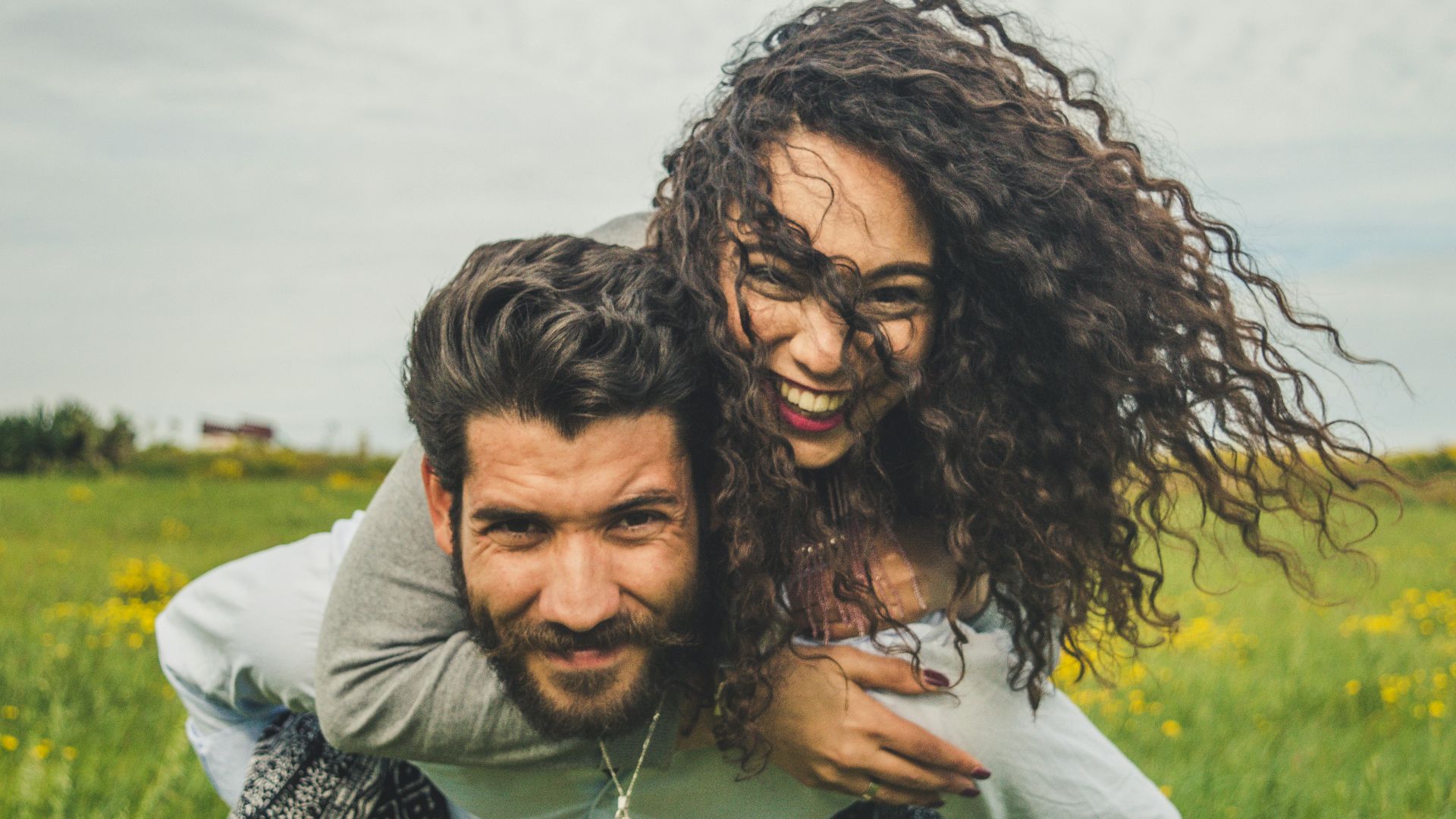 woman riding on man's back on green field