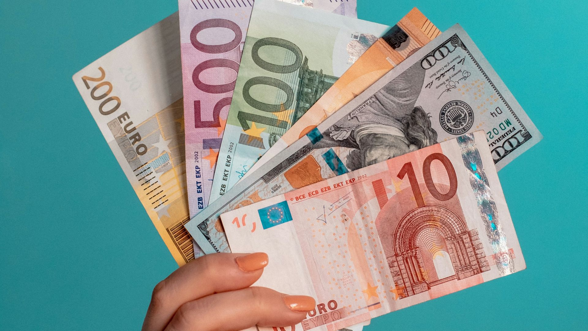 person holding fan of 100 us dollar bill