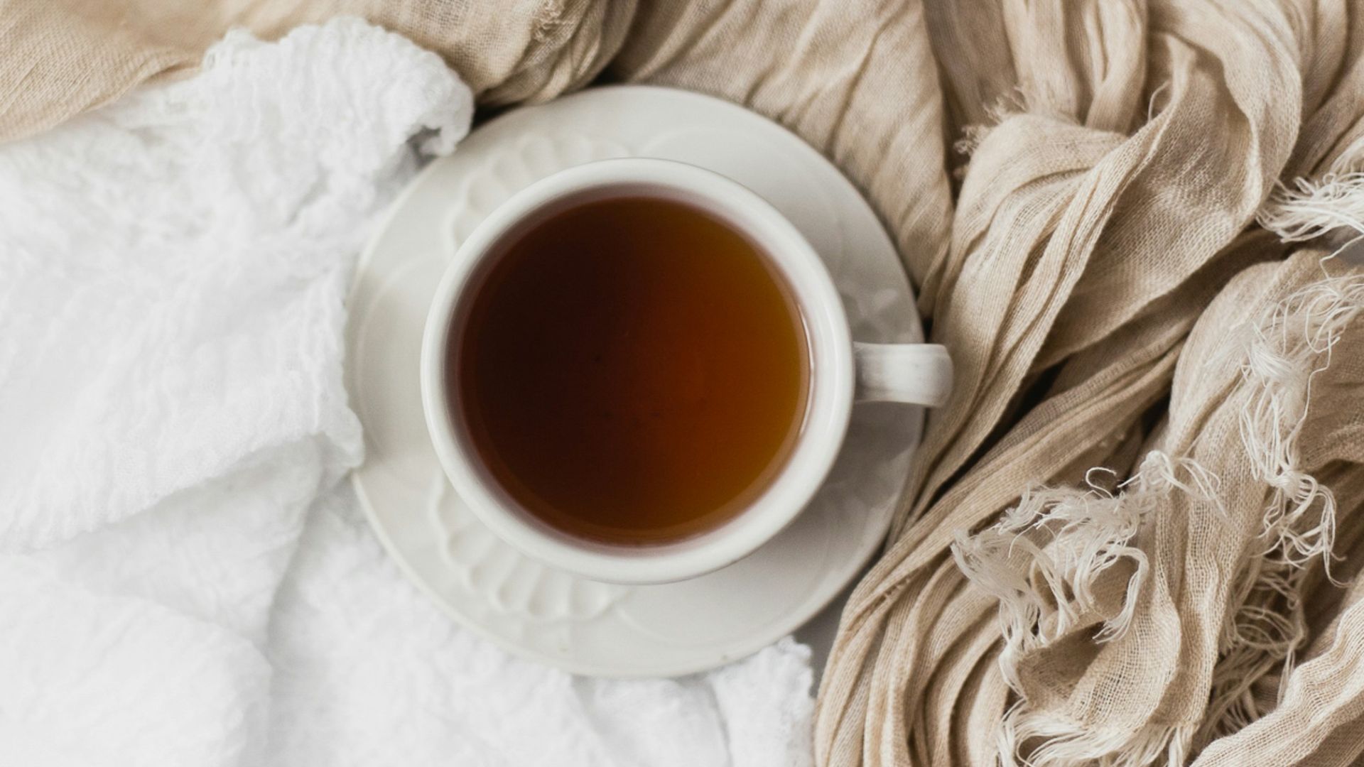 tea filled white ceramic mug on white ceramic saucer