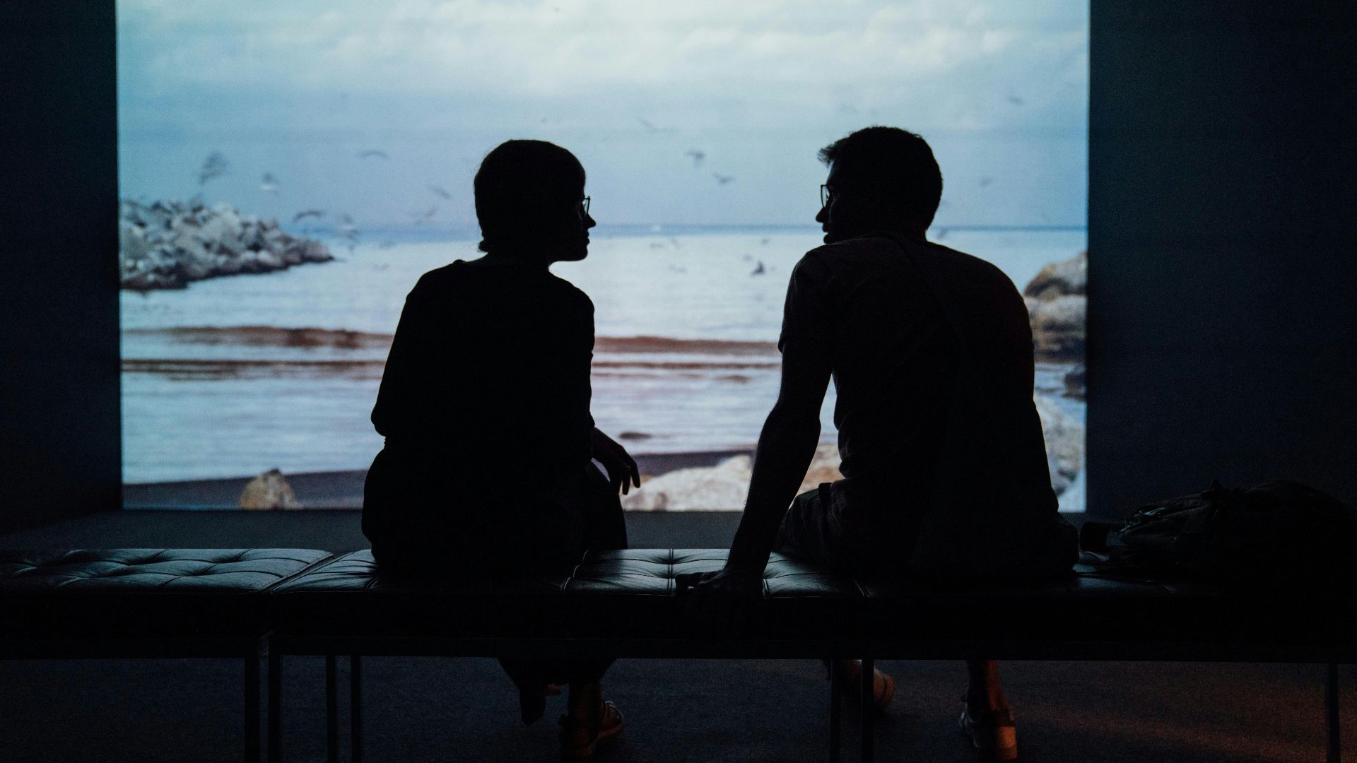 silhouette of man and woman sitting on ottoman