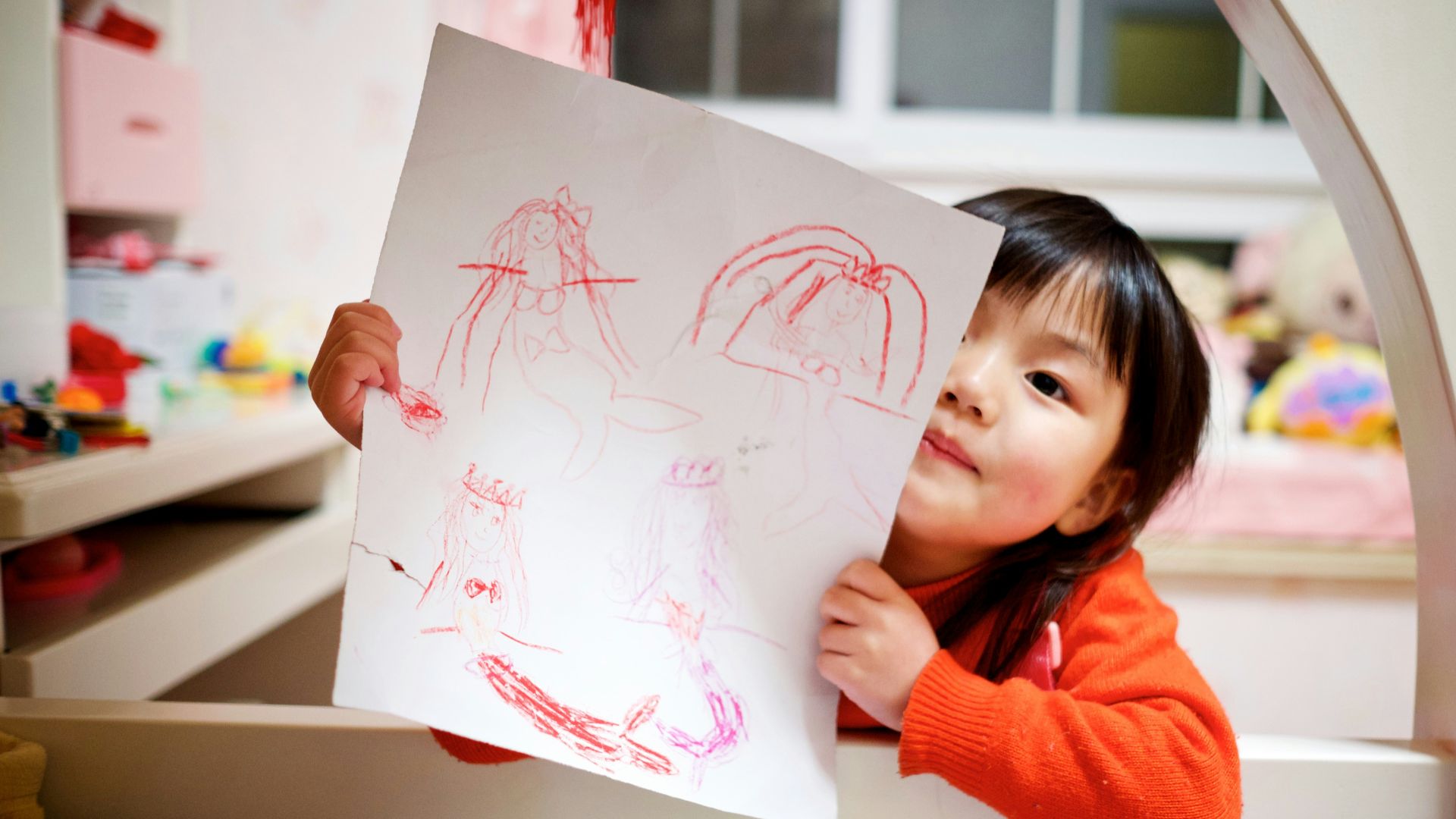 girl holding paper with drawing