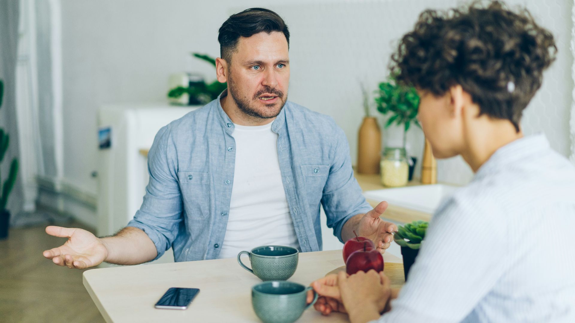 a man sitting at a table talking to a woman